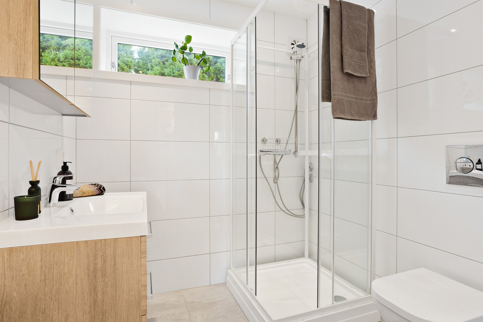 Badet i underetasjen ble oppgradert i 2021 og har gulvvarme og fliser på gulv og vegger. Malt, slett himling med innfelte downlights. Badet inneholder servant, veggmontert wc og dusjkabinett. Galleribilde