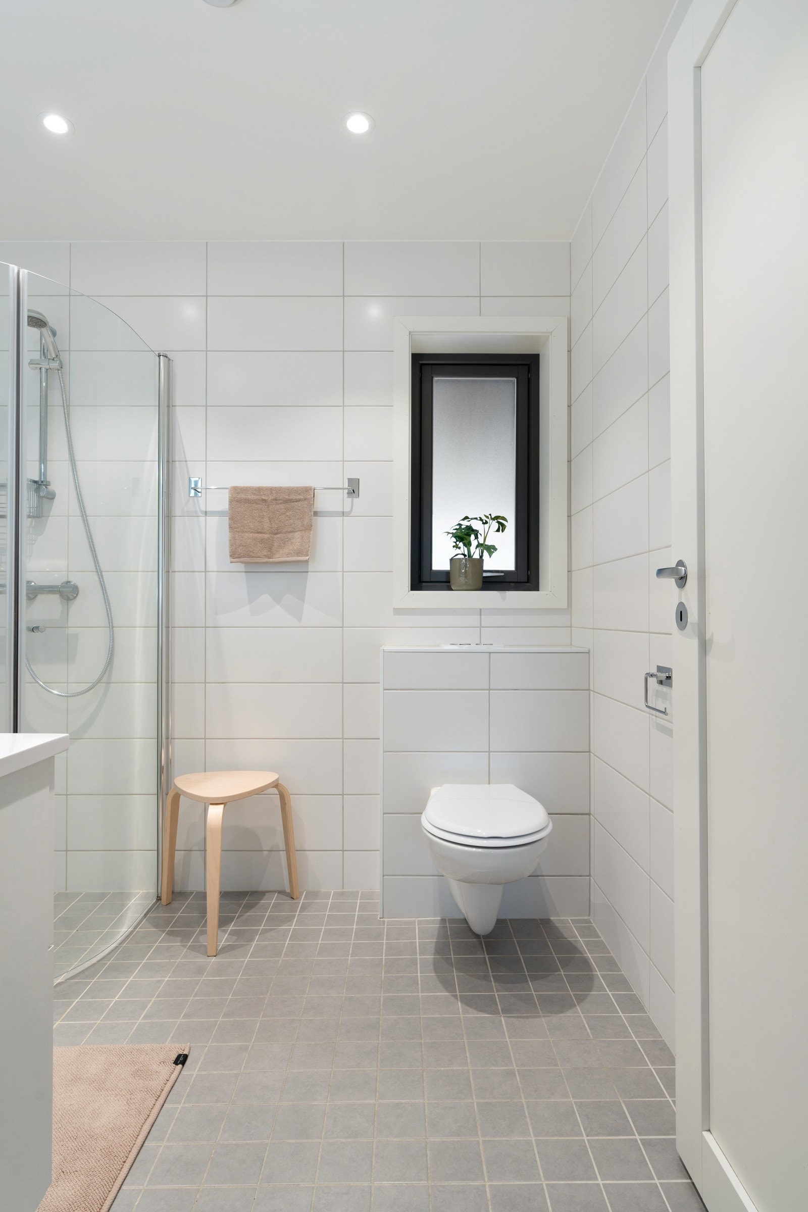 Badet er utstyrt med innfelbar dusj og vegghengt toalett for et rent og moderne uttrykk.