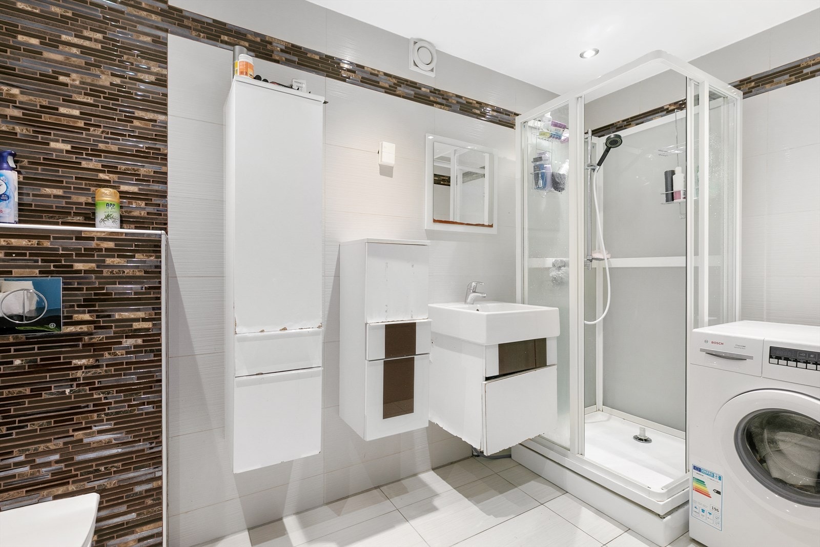 Badet på 3,25 m² er helfliset og har vegghengt toalett, dusjkabinett og opplegg for vaskemaskin. Galleribilde