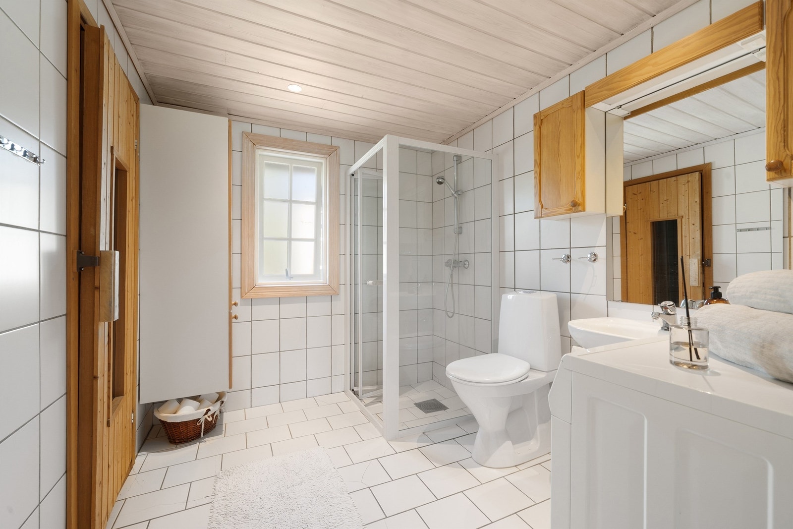 Lyst bad med varmekabler, wc, dusjhjørne, servant, overskap, høyskap, og inngang til tenkt badstue. Galleribilde