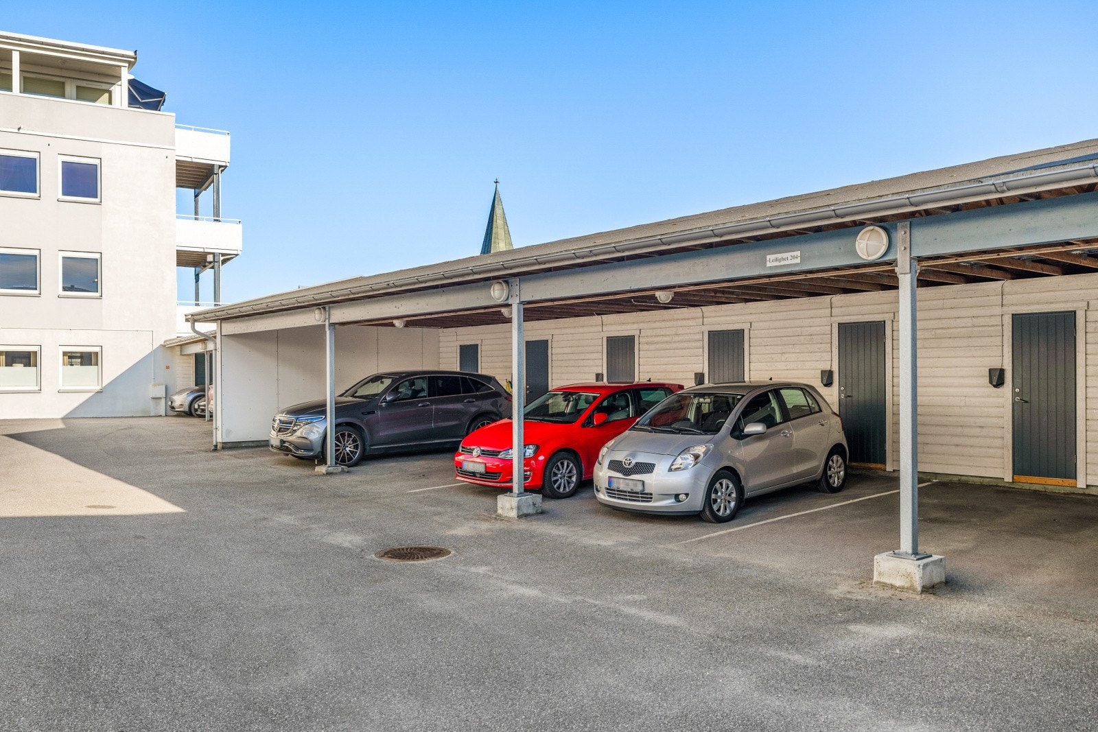 Det er parkering i carport med ladestasjon for el-bil. Galleribilde