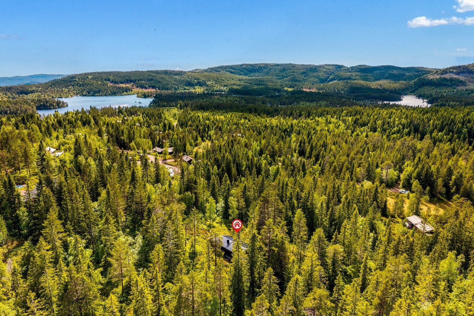 Hytta ligger fint for seg selv, omkranset av skog Galleribilde