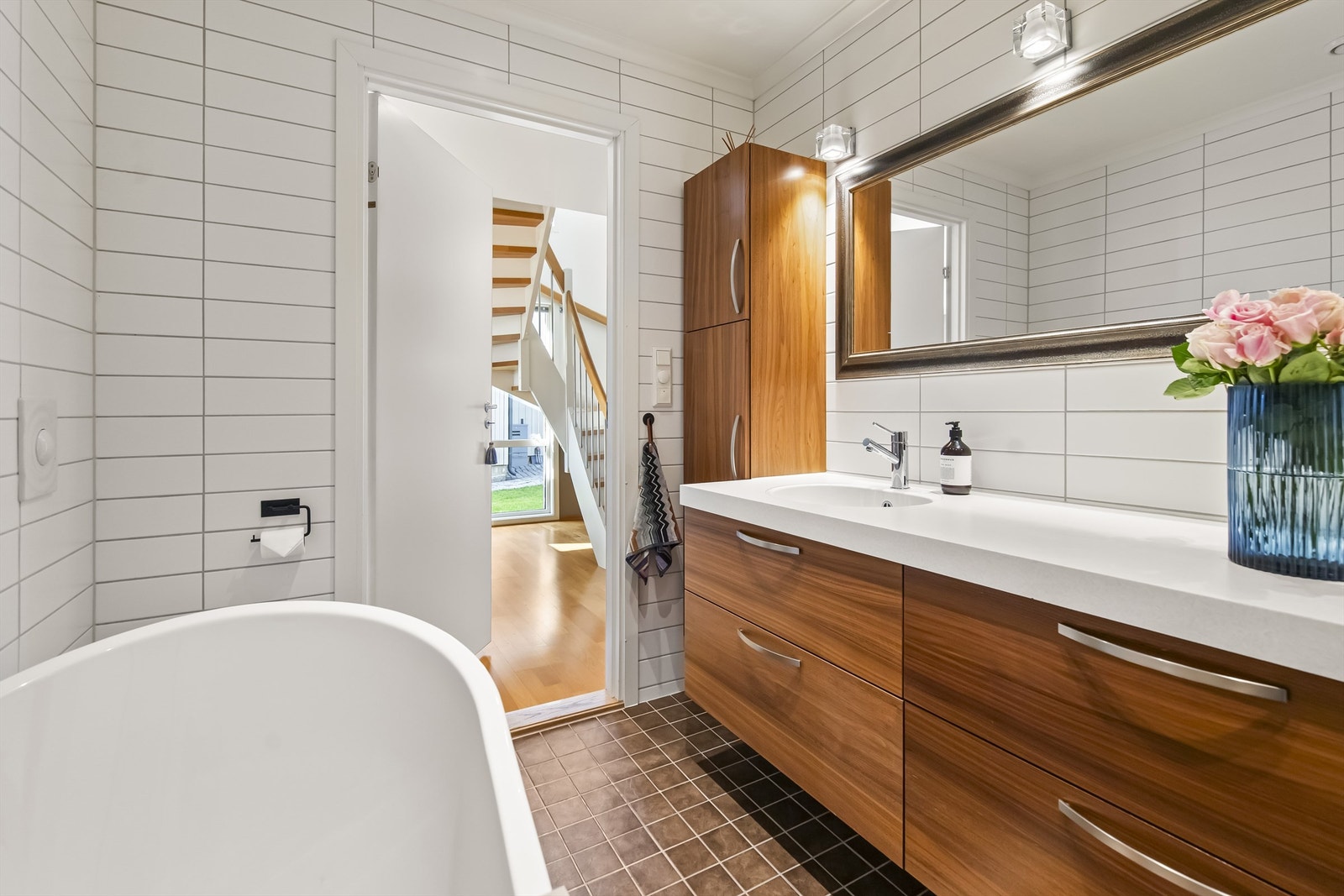 Badet er innredet med badekar, servant i innredning med sideskap og vegghengt toalett Galleribilde