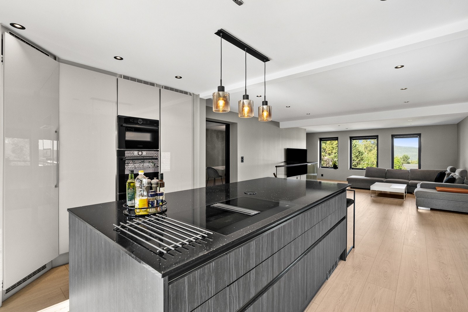 Kjøkken fra 2021 med påkostede detaljer, integrerte hvitevarer og stor kjøkkenøy koketopp med integrert ventilator. Galleribilde