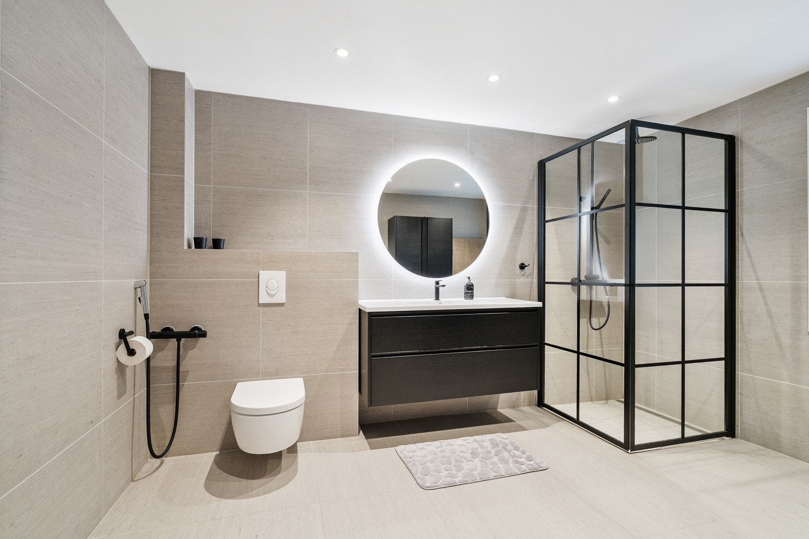 Elegant og påkostet baderom med lekre kontraster i sort og hvitt. Stort speil med belysning og dusj med glassvegger gir en følelse av luksus og velvære. Galleribilde