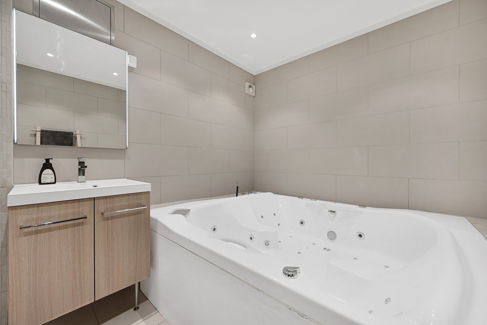 Flott baderom i underetasjen med et flott badekar og en innredning med underskap og vegghengt speil. Galleribilde