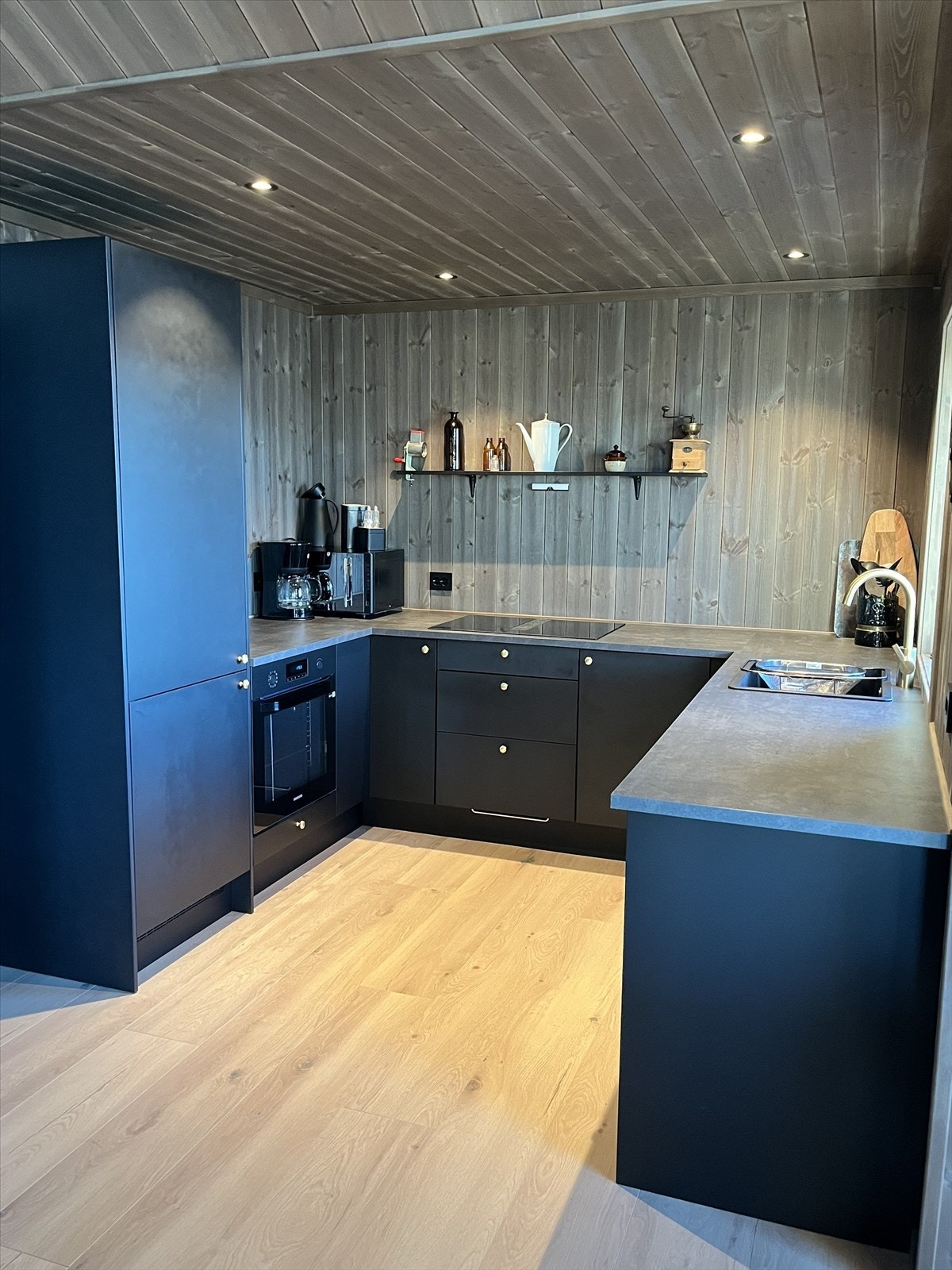 Moderne kjøkkeninnredning i mørk utførelse med laminat benkeplate. Løsningen uten overskap gir et luftig uttrykk. Galleribilde