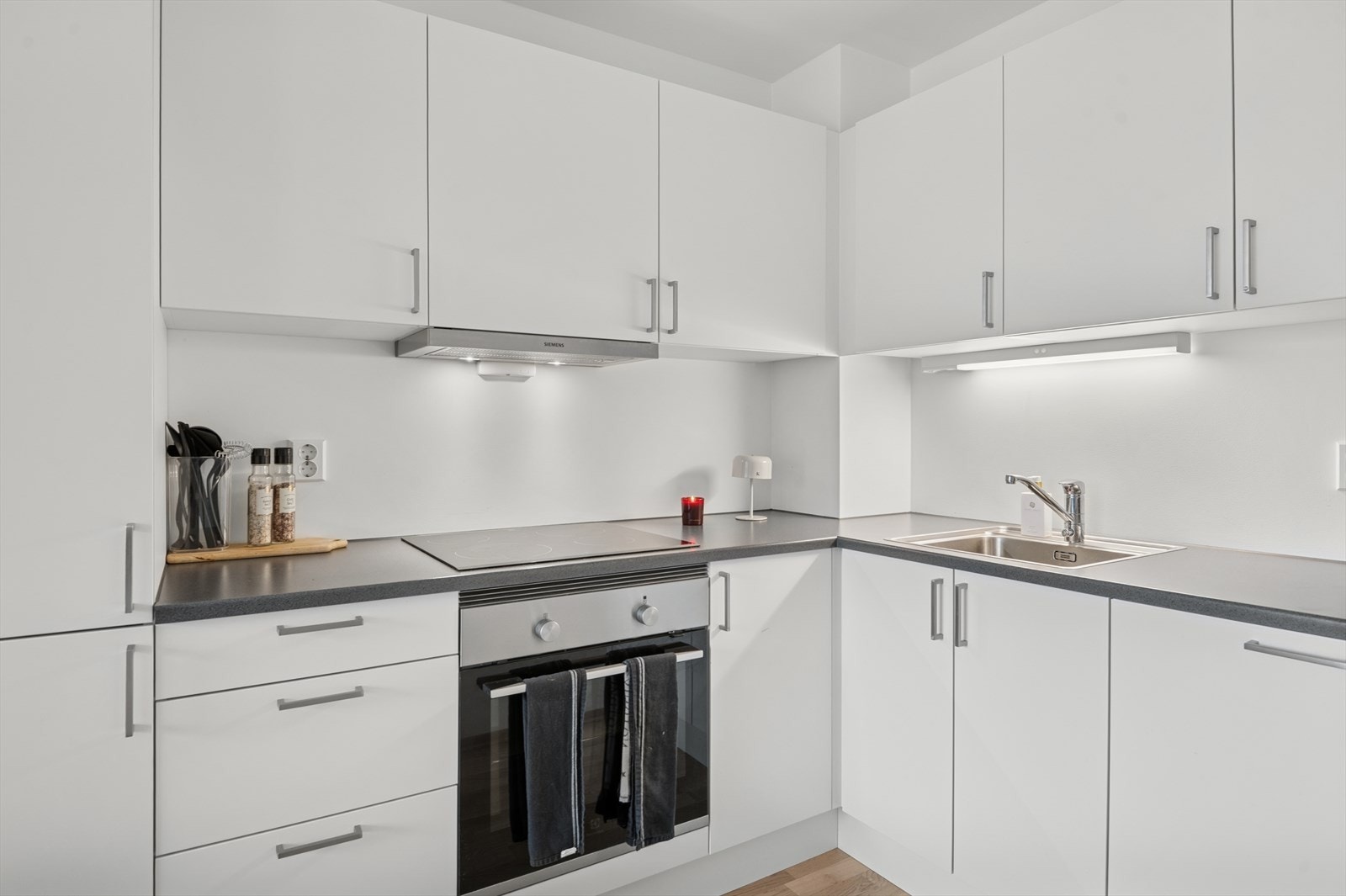 Kjøkkenet har hvitt glatt kjøkken med benkeplate av laminat, og integrerte hvitevarer av keramisk koketopp, komfyr, oppvaskmaskin og kjøleskap med fryser. Galleribilde