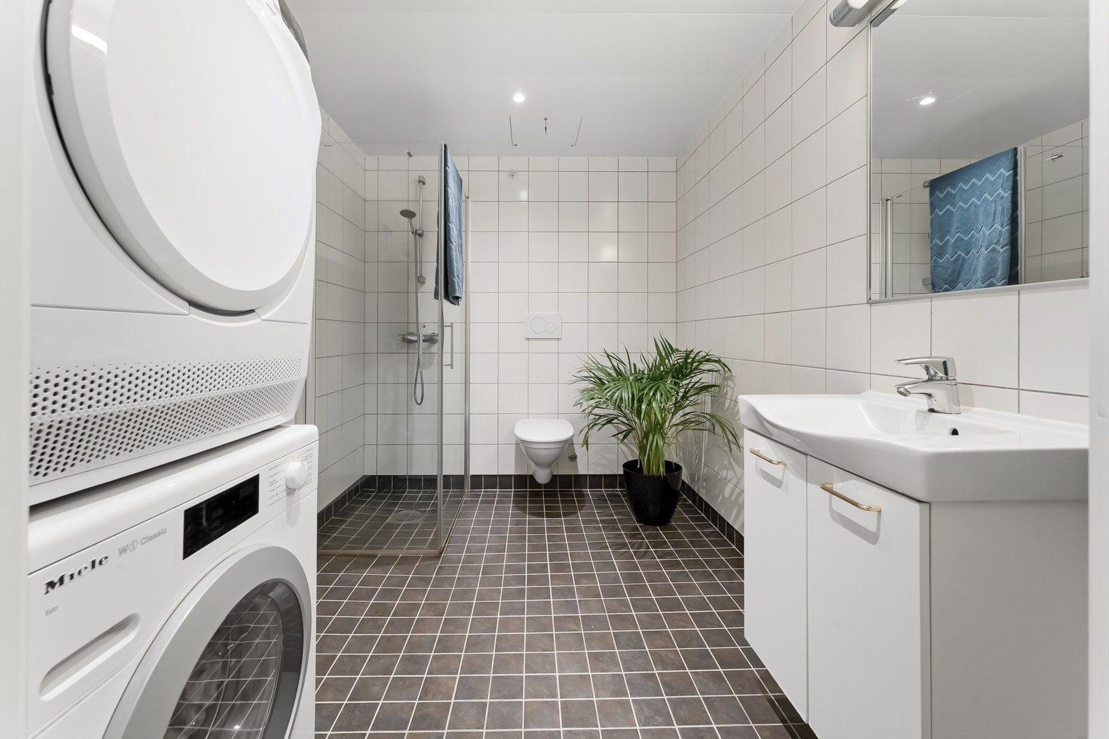 Pent og flislagt baderom med gulvvarme og downlights. Opplegg for vaskemaskin og tørketrommel Galleribilde
