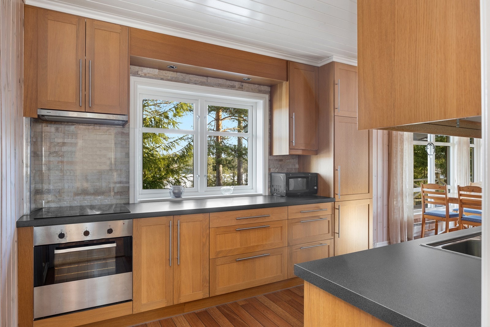 Pent kjøkkeninnredning fra 2009 med fronter i eik, laminerte benkeplater og takhøye skap. Galleribilde