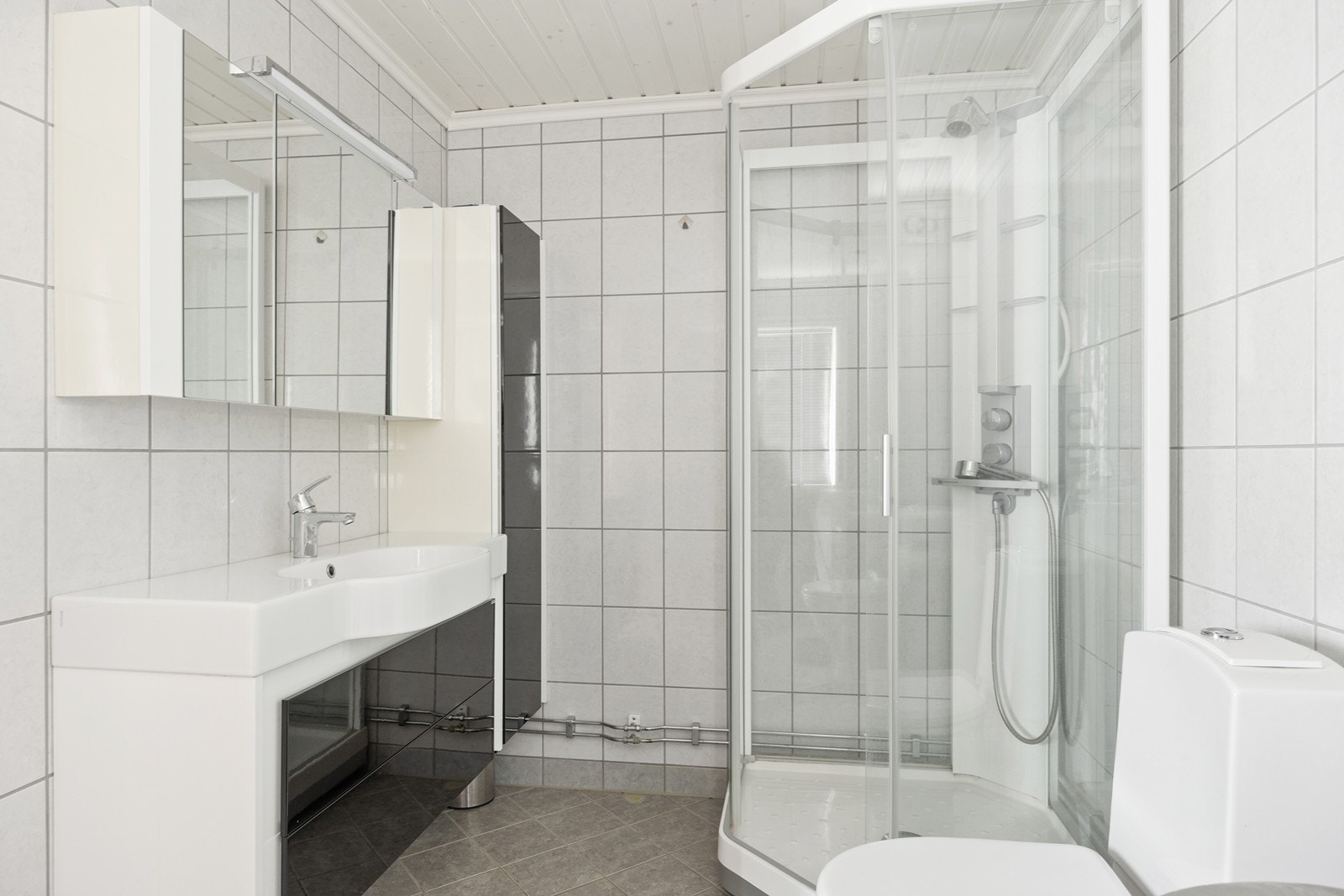 Bad innredet med nedfelt servant, toalett og dusjkabinett. Galleribilde