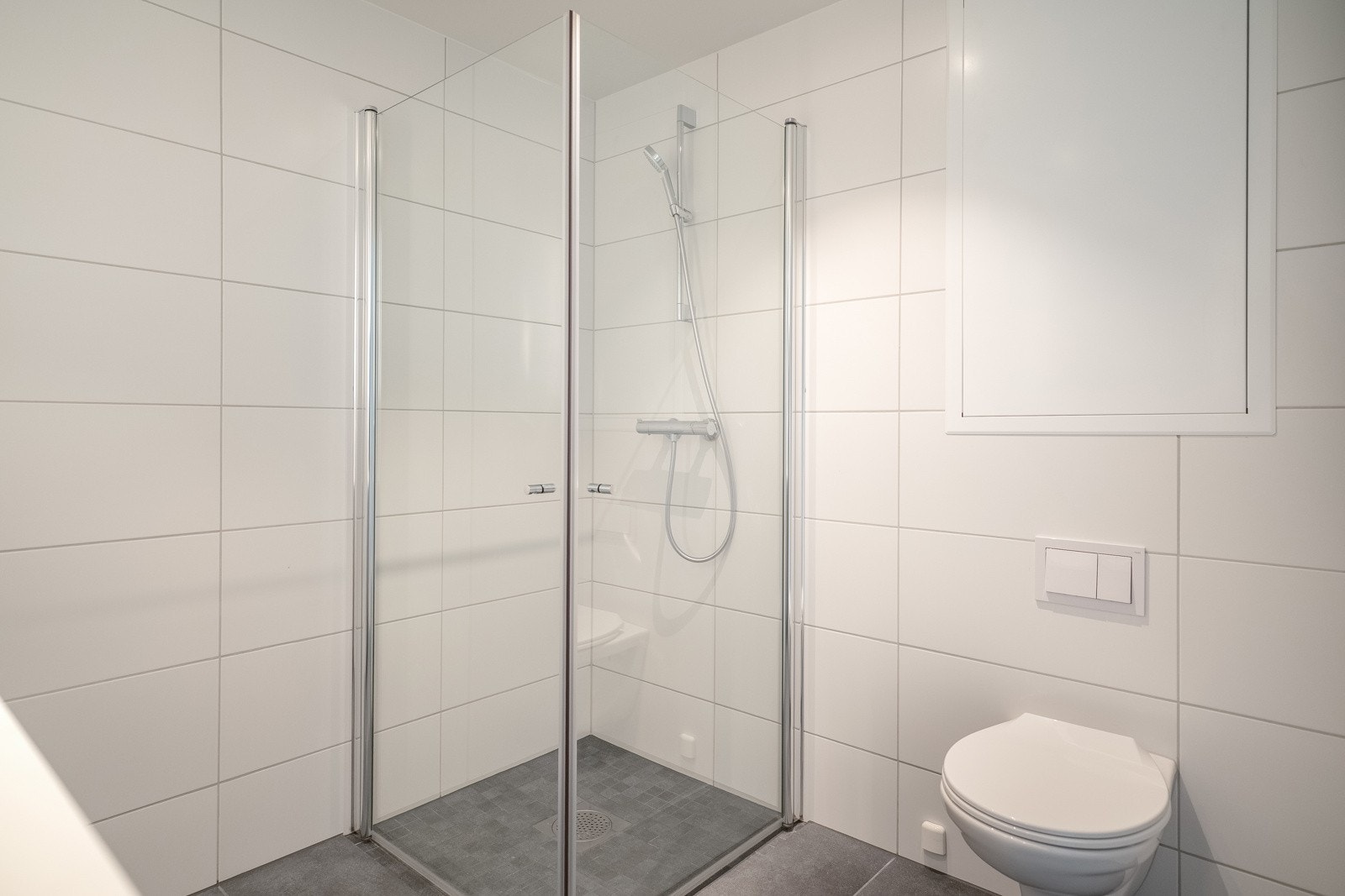 Badet er videre utstyrt med servant med innredning fra HTH, vegghengt toalett og dusjnisje med glassdør. Galleribilde