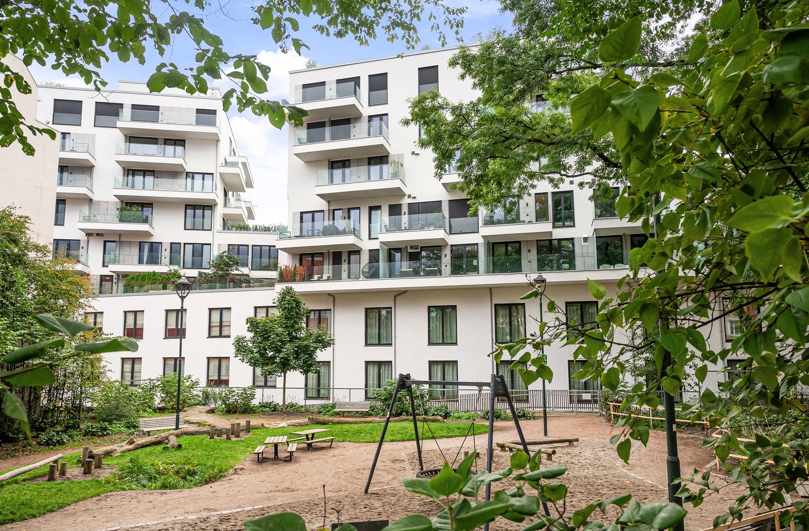 Velstelt fellesområde med grøntarealer og lekeplass i indre gårdsrom. Galleribilde