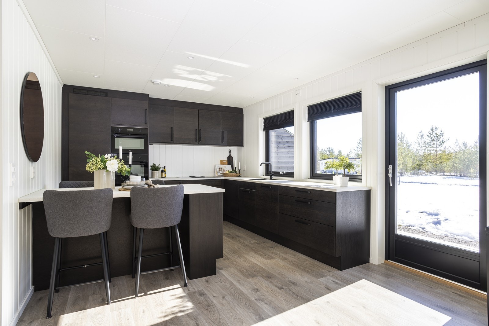 Kjøkkenet har en stilren og moderne innredning med mørke fronter og en laminat benkeplate med nedfelt vask. Galleribilde