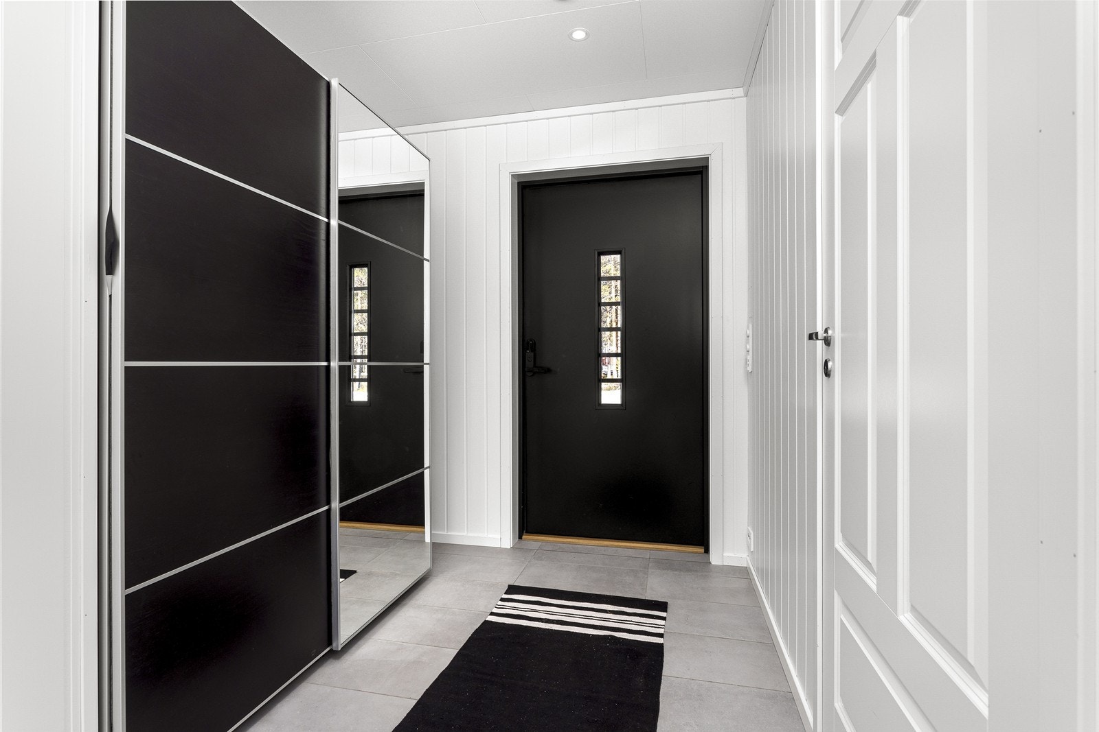 Man ønskes velkommen inn i en romslig entré med med flislagt gulv og elektriske varmekabler, utstyrt med en skyvedørsgarderoben som gir godt med oppbevaring til sko og yttertøy. Galleribilde