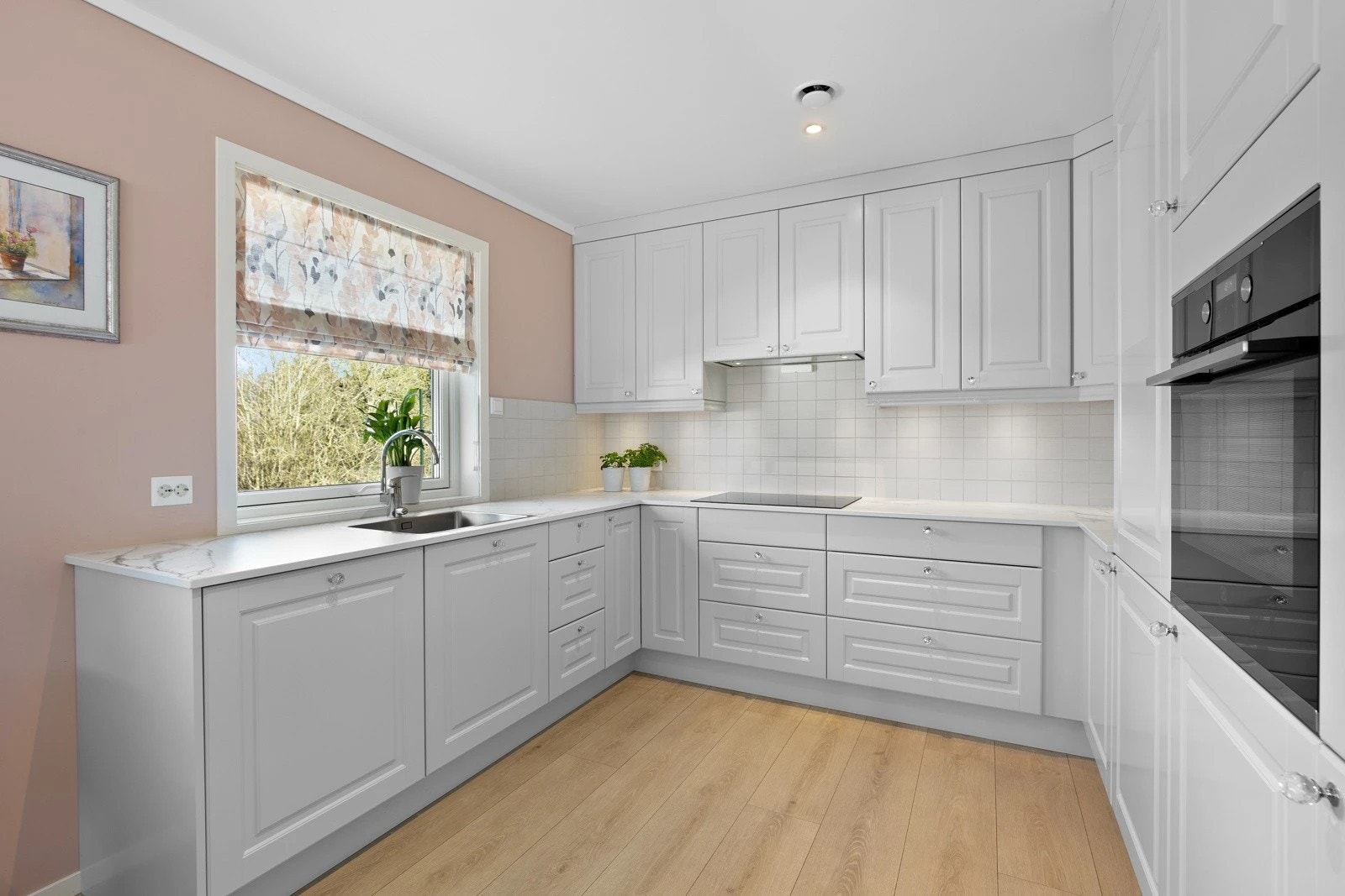 Lekkert og minimalistisk design med elegante profilerte fronter og keramisk benkeplate. For et luftigere uttrykk er flere overskap droppet til fordel for åpne flater, samtidig som det er rikelig med skap- og benkeplass. Galleribilde