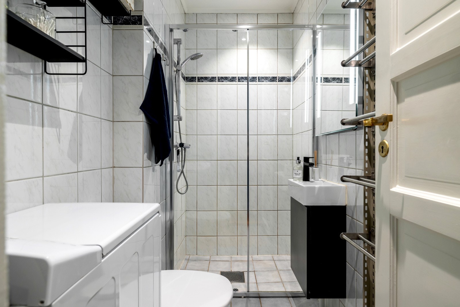 Badet er helfliset med lyse fliser på vegger og gulv, noe som gir et tidløst og rent uttrykk. Galleribilde