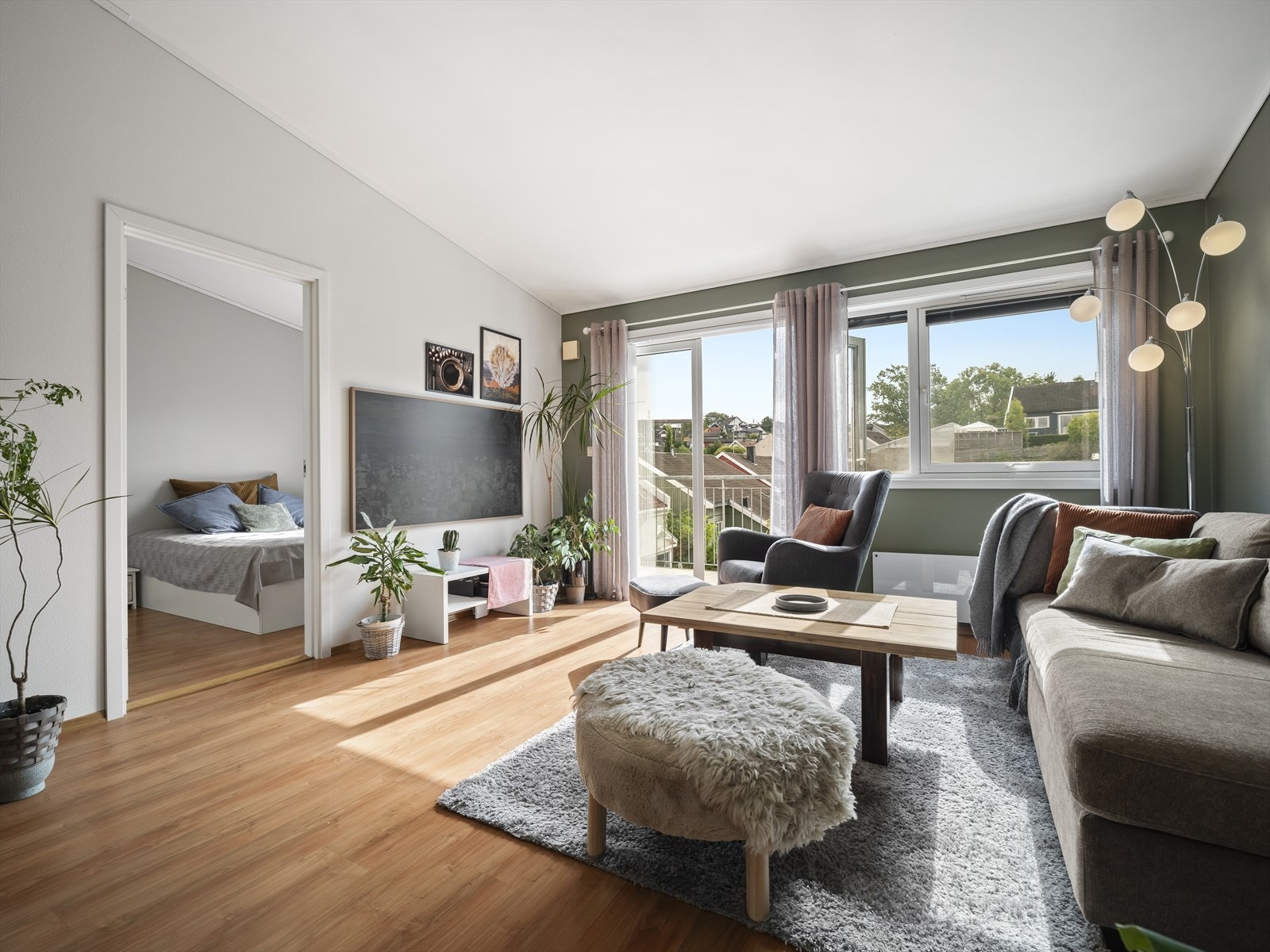 Stuen har laminat på gulv og lysmalte overflater med fine kontrastvegger malt i en mørk grønnfarge. Galleribilde