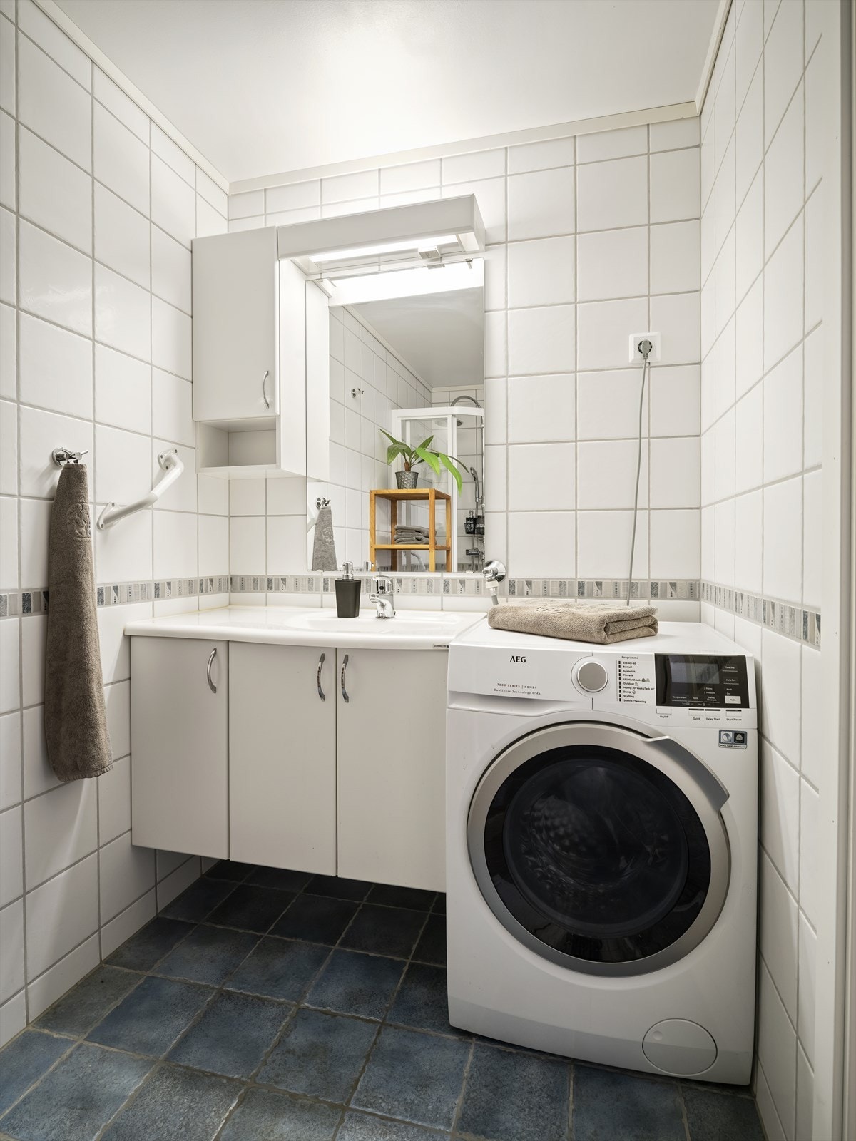 Leiligheten har et lyst flislagt baderom fra byggeåret 2006. Lys baderomsinnredning med heldekkende servant, speil med belysning og vegghengt skap over. I hjørnet er det plass og opplegg for vaskemaskin, samt tørketrommel over om ønskelig. Galleribilde