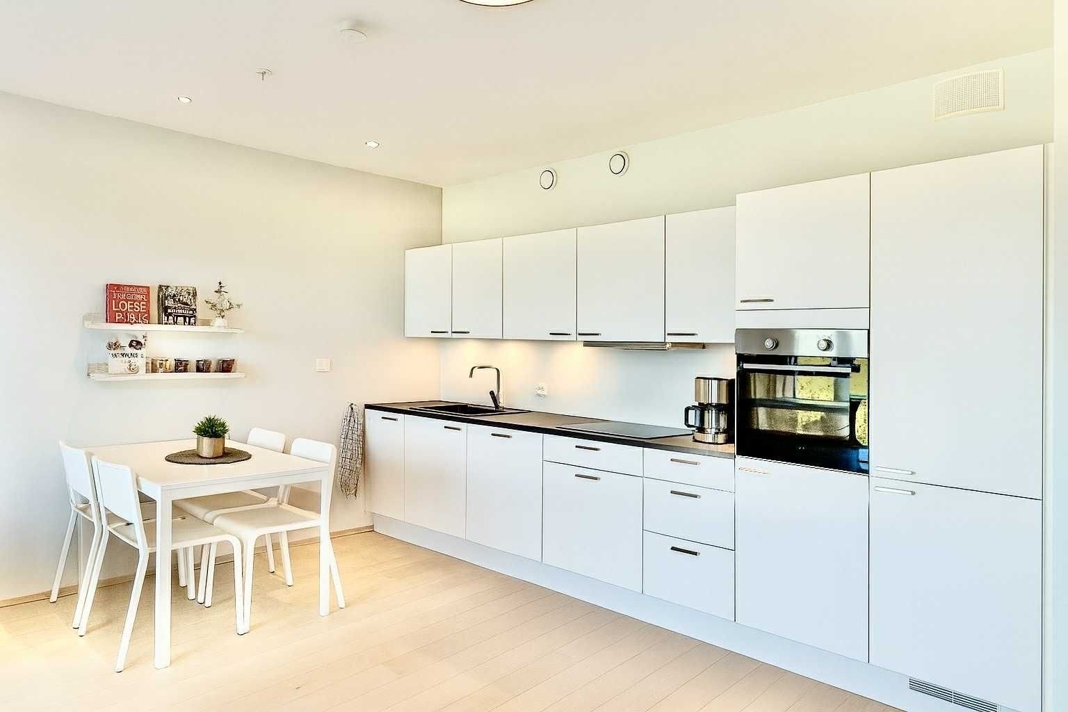 Moderne kjøkken med slette fronter. Hvitevarer er integrert og består av stekeovn med induksjonstopp og komfyrvakt, oppvasmasking med vannstopper og kjøl/frys. Galleribilde