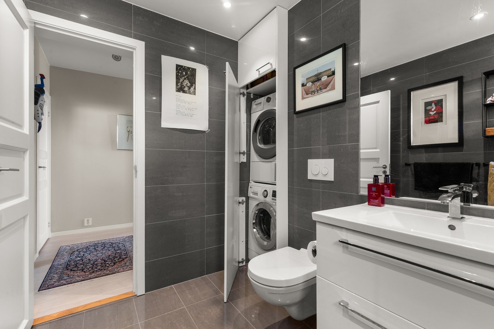 Badet har opplegg for vaskemaskin og tørketrommel i egen nisje, skjult bak hvite skapfronter. Galleribilde