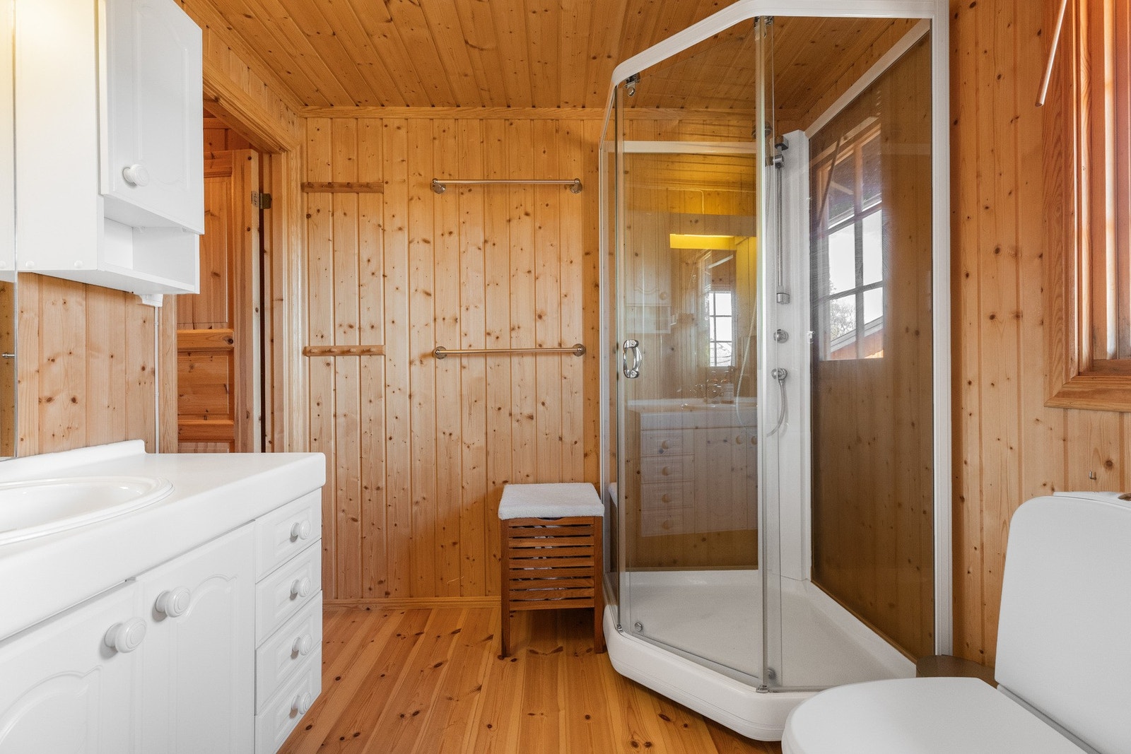 Badet har panel på vegger og tregulv. Innredning med under- og overskap, nedfelt servant i benk Galleribilde