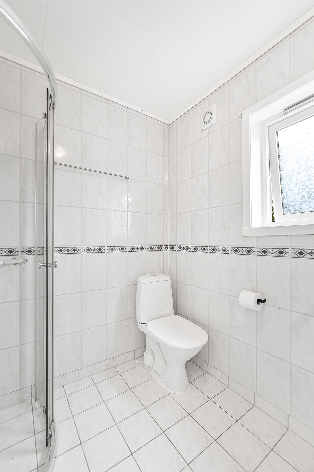 Badet er innredet med toalett, dusjhjørne og servant med skap. Galleribilde