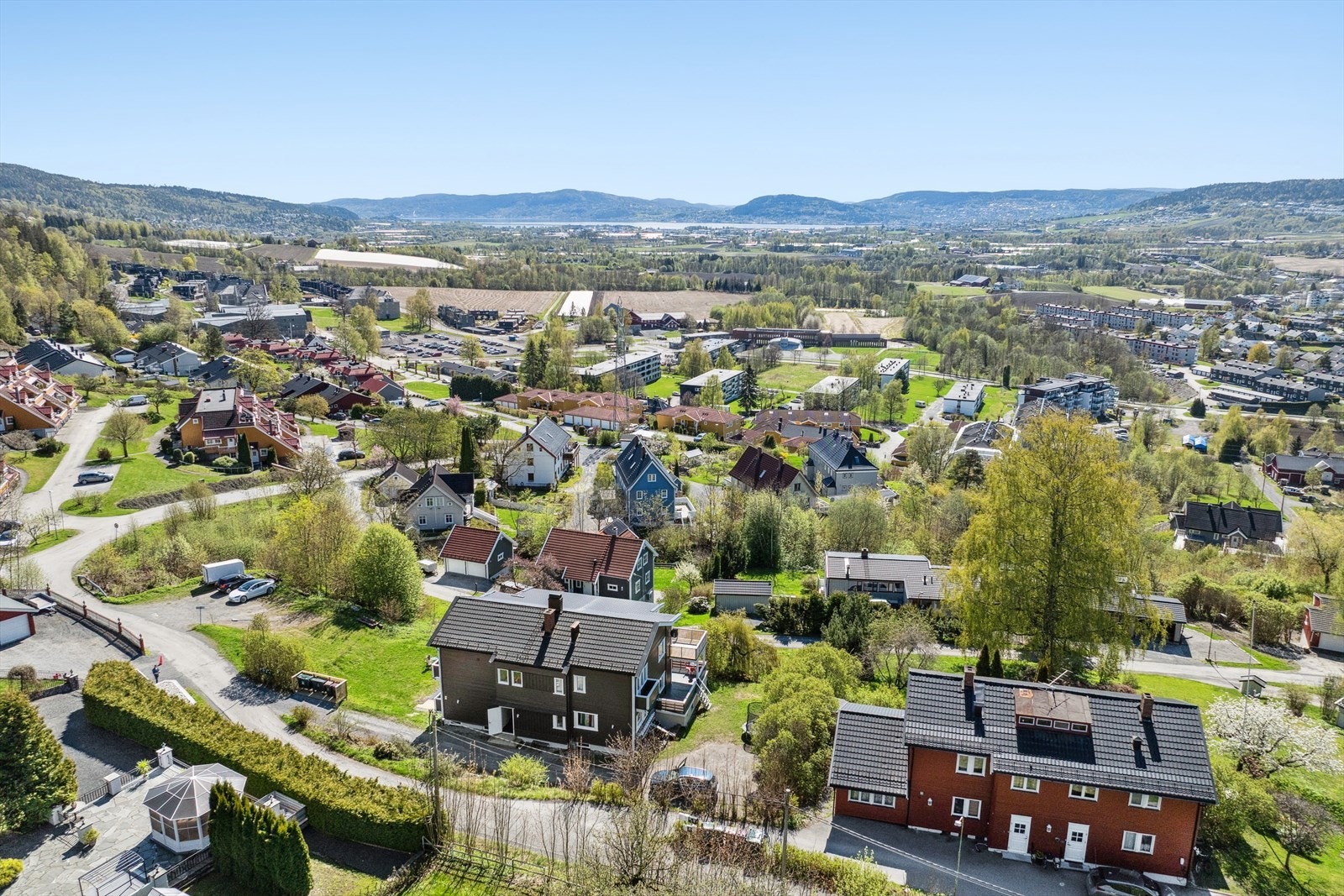 Stor tomt opparbeidet med gruset gårdsplass, innkjørsel, gressplen og beplantning. Galleribilde