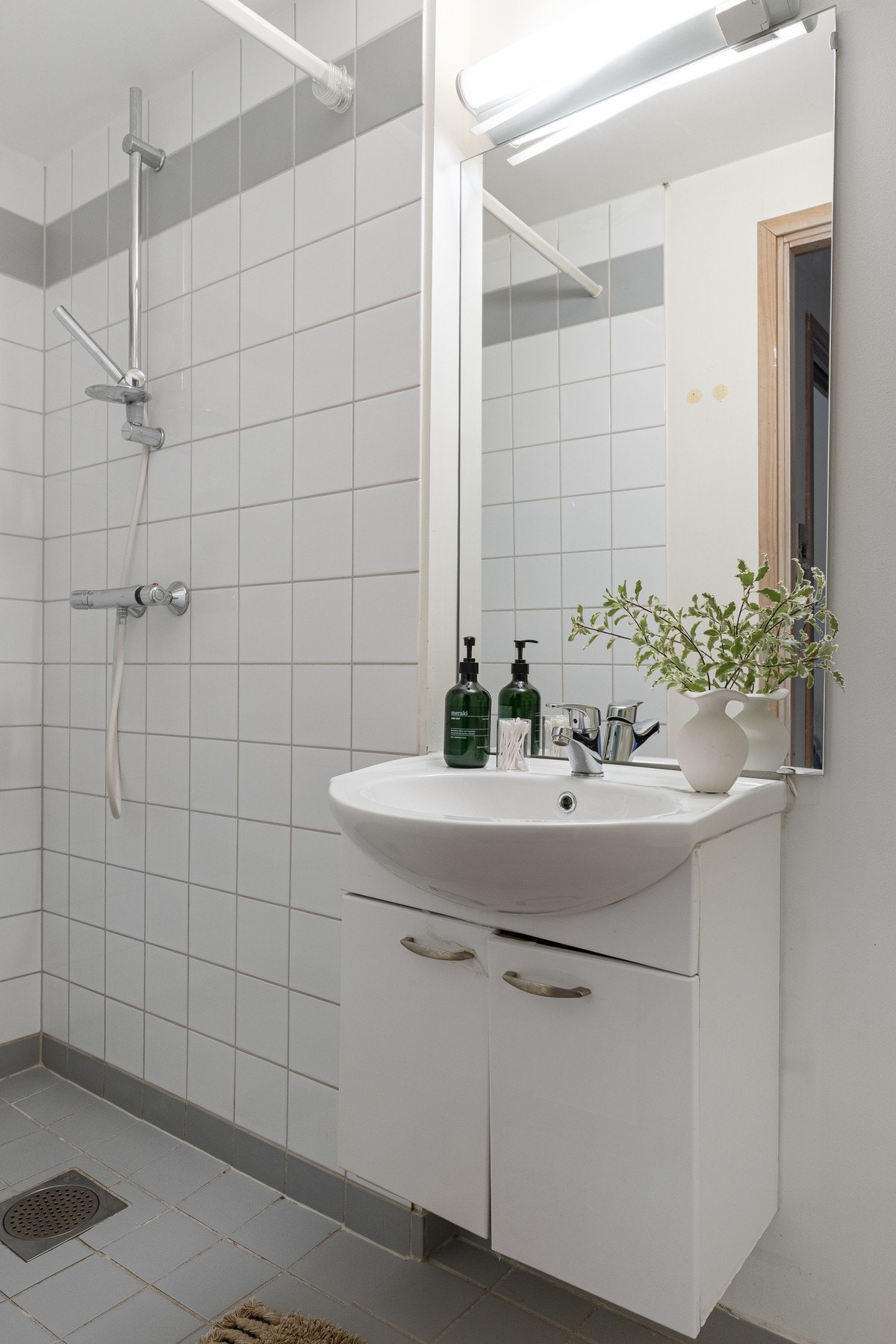 Badet inneholder speil, servant med underskap, dusjhjørne og toalett. Galleribilde