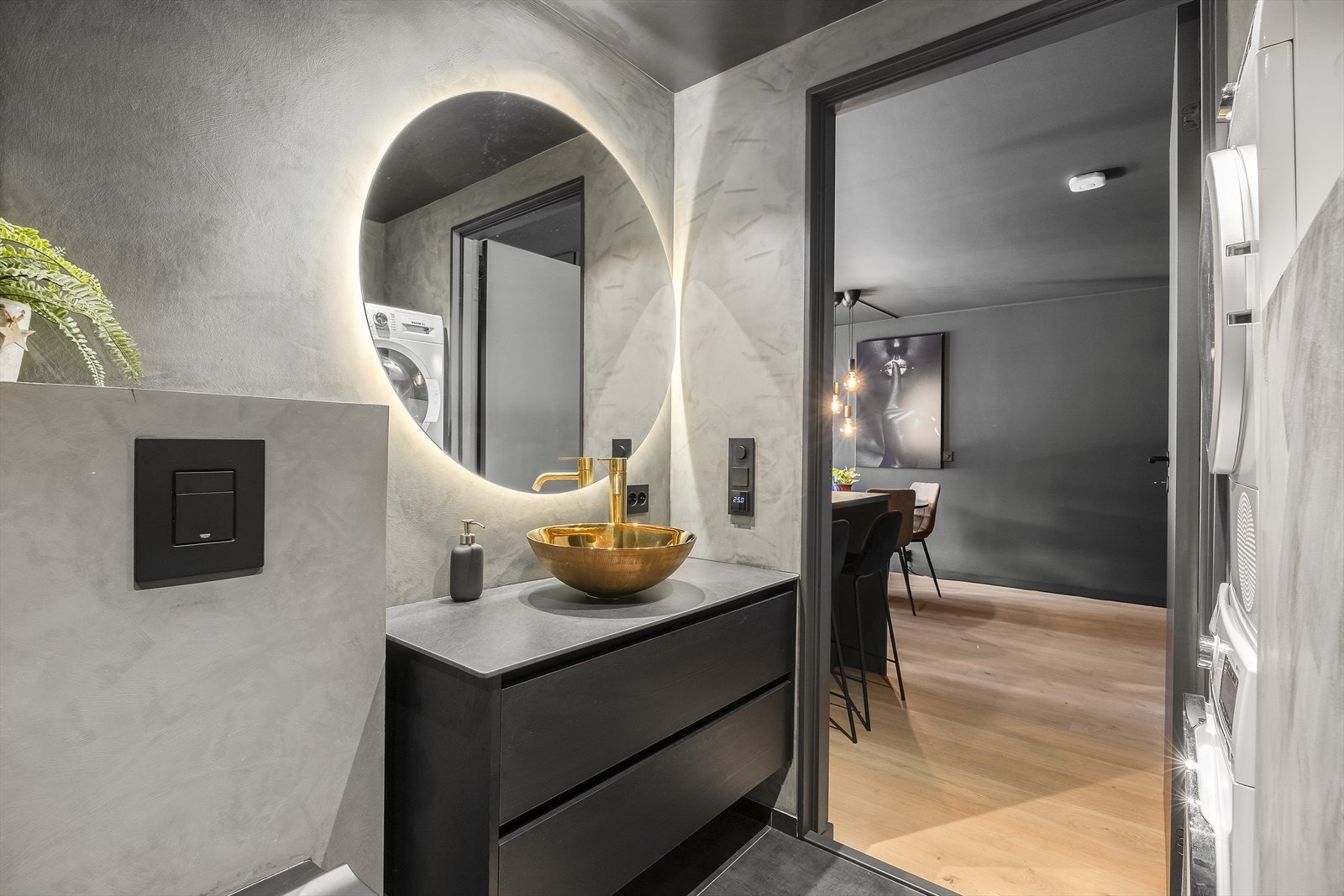 Moderne baderomsinnredning med servant, speil med belysning, benkeskap med glatte fronter, vegghengt toalett med innebygget sisterne samt dusj med glassvegg. Galleribilde