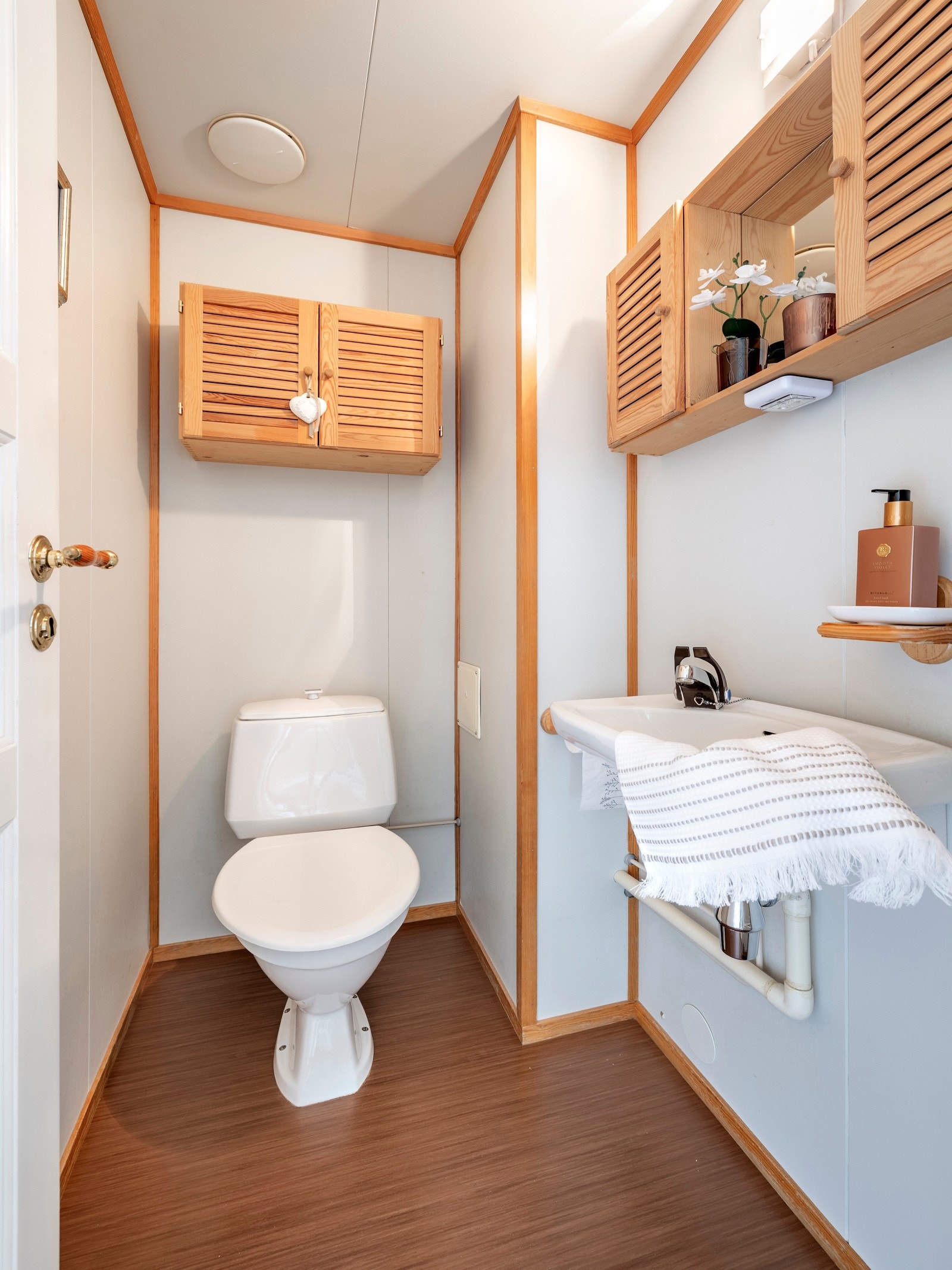 På wc-rommet er det hvite vegger og belegg på gulvet, og i tillegg til et gulvmontert toalett har rommet en servant, et veggskap og et speilskap. Galleribilde