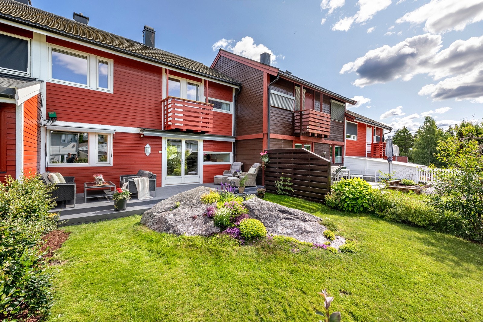 Terrassen ligger i flukt med en solrik, koselig hage med plen, prydbusker, fjell i dagen og fargerike blomster. Vinduer og dører ble skiftet i 2018, og huset er sist malt utvendig i 2019. Galleribilde