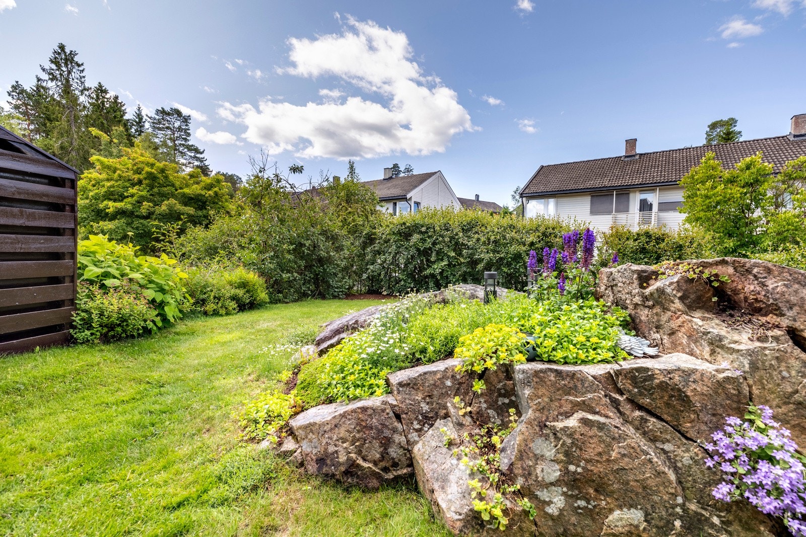 Terrassen ligger i flukt med en solrik, koselig hage med plen, prydbusker, fjell i dagen og fargerike blomster. Vinduer og dører ble skiftet i 2018, og huset er sist malt utvendig i 2019. Galleribilde