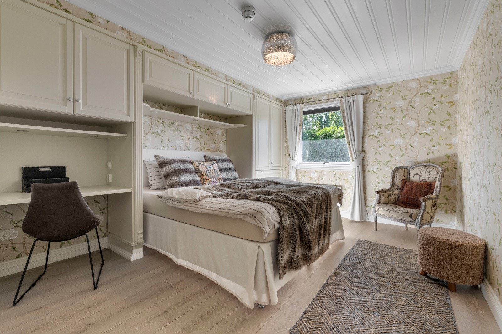 Med tapetet som går igjen på veggene skapes en rød tråd i interiøret. Dobbeltsengen er innrammet av skapplass - en smart utnyttelse av rommet. Galleribilde