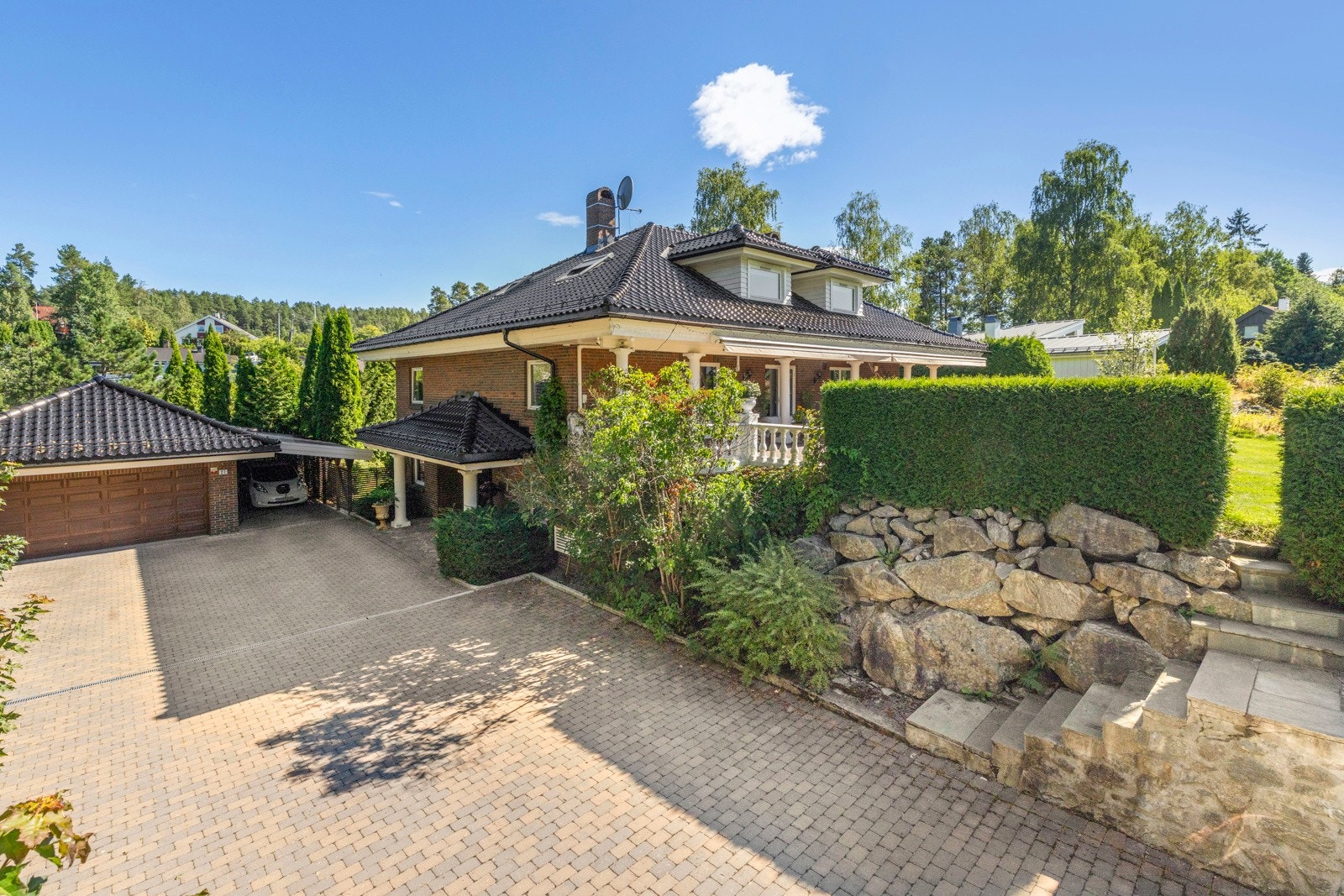 Stensatt gårdsplass gir et ryddig og tiltalende inntrykk, med rikelig plass til parkering. På eiendommen er det både dobbelgarasje, carport og praktiske lagringsboder. Galleribilde