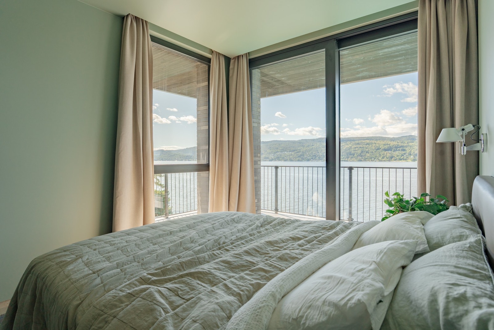Et lyst og harmonisk soverom med store vindusflater som slipper inn rikelig med dagslys og gir en fantastisk utsikt mot fjorden. Galleribilde