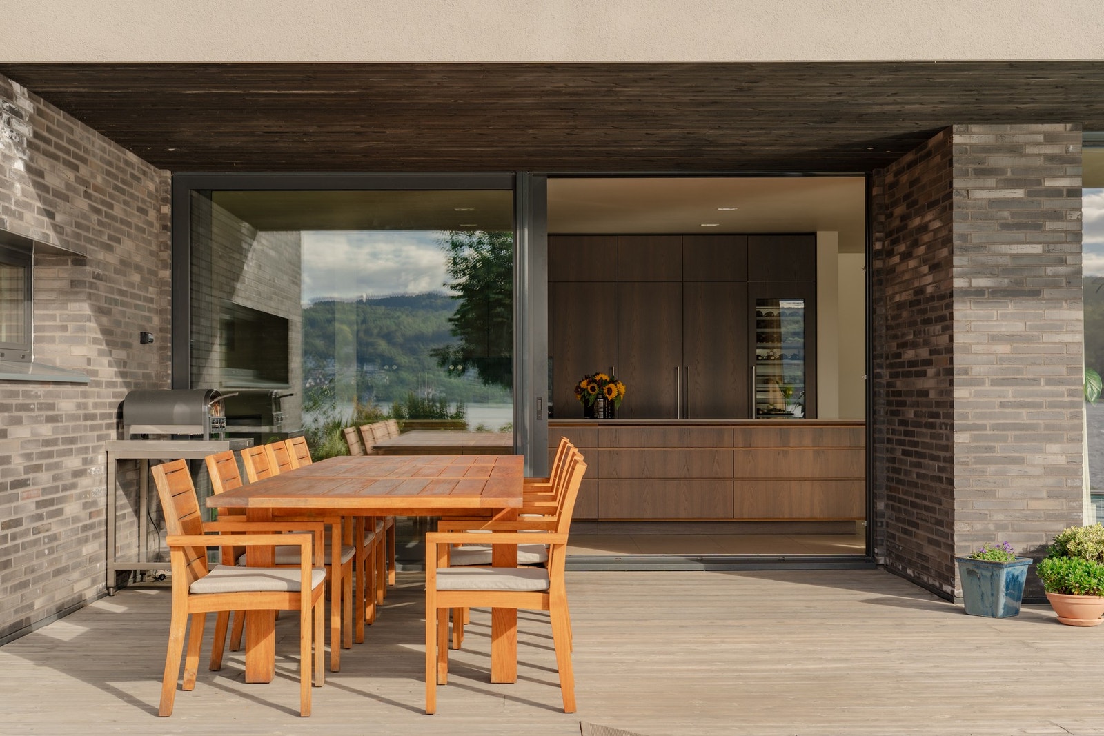 Stor spiseplass ute med sømløs overgang til innendørs kjøkken. Galleribilde