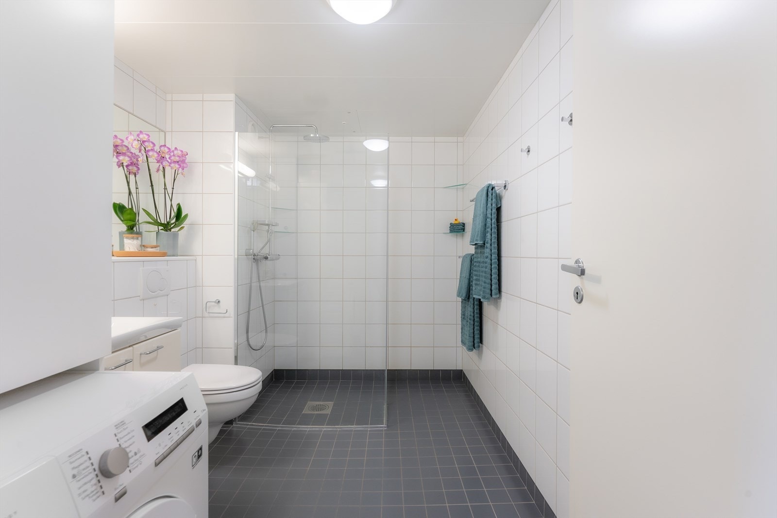 Badet er innredet med dusjnisje med glassvegg, vegghengt toalett og servant i skapinnredning. Galleribilde