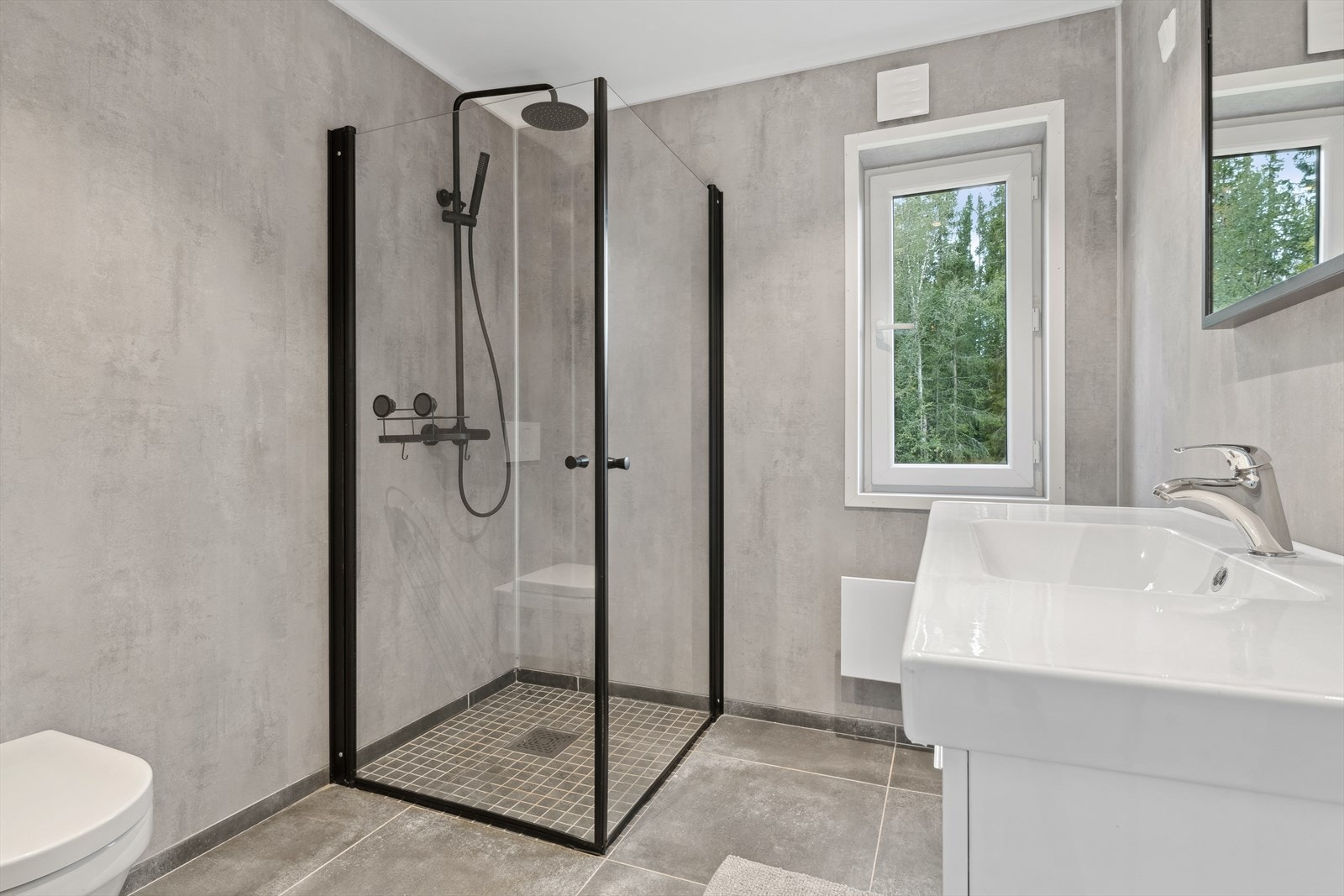 Pent bad fra ca 2020 med flis på gulv og våtromsplater på vegger. Downlights i himling. Panelovn. Galleribilde