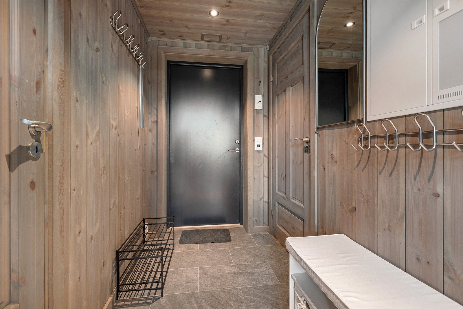 Pen flislagt gang med varmekabler. Her er det plass til å henge fra seg yttertøy og sko. Galleribilde