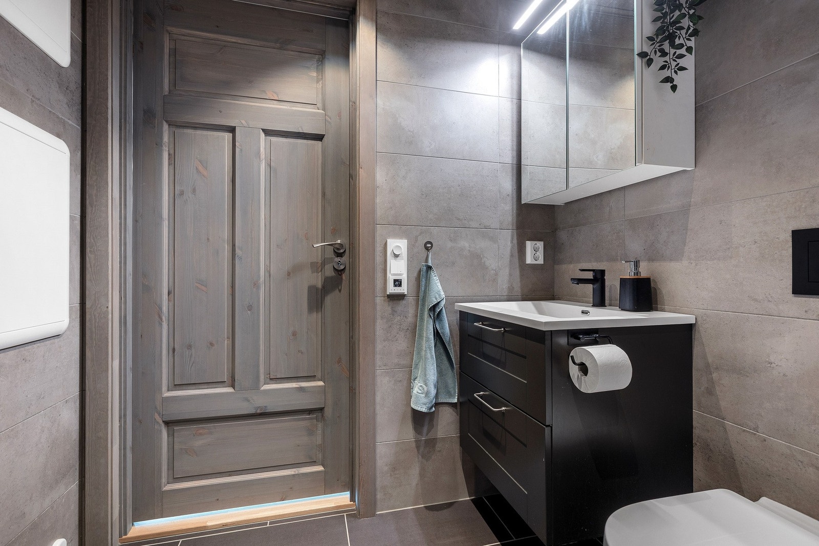 Pen baderomsinredning med servant og speilskap med integrert lys over. Galleribilde