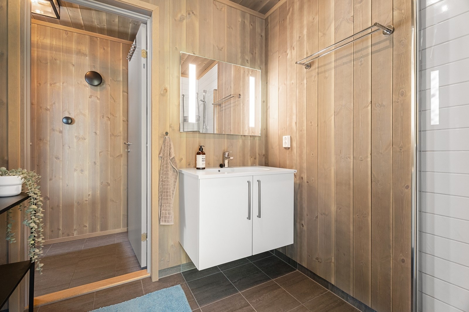 Videre er badet innredet med servant med underskap, speil med lys og gulvstående toalett. Galleribilde