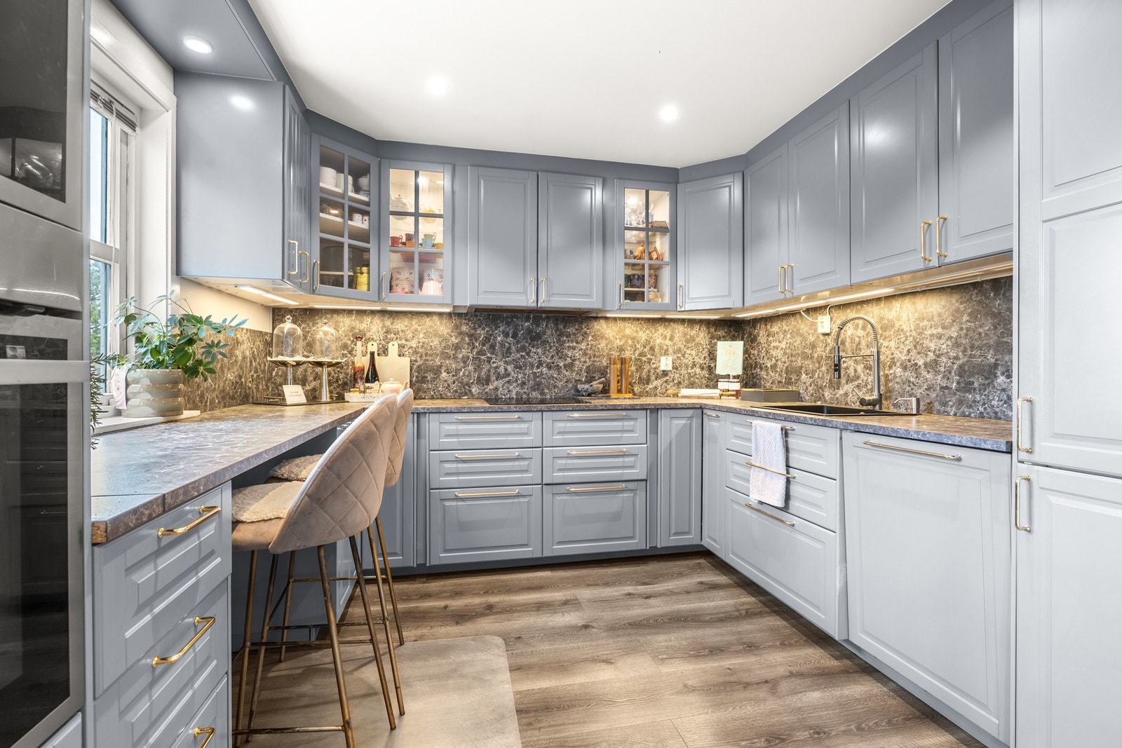 Boligen har et stilfullt og moderne kjøkken fra Ikea med grå, profilerte fronter og enkelte overskap med glassfronter som gir et lett og elegant uttrykk. Galleribilde