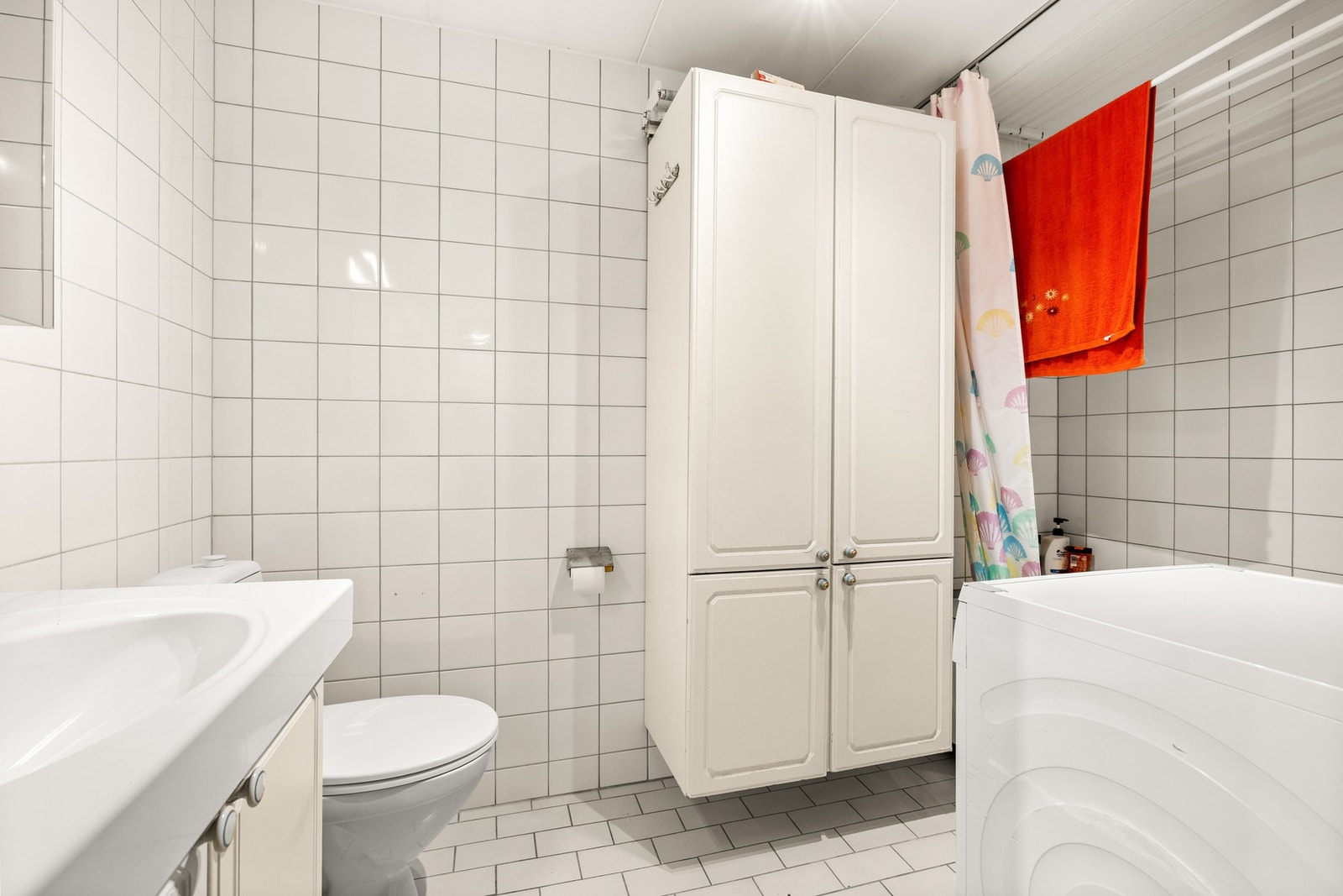 Rommet har flislagte gulv- og veggflater, samt malte plater i himling. Innredet med badekar, klosett, servant med skapinnredning, speilskap og plass for vaskemaskin. Sluk i plastkonstruksjon. Galleribilde