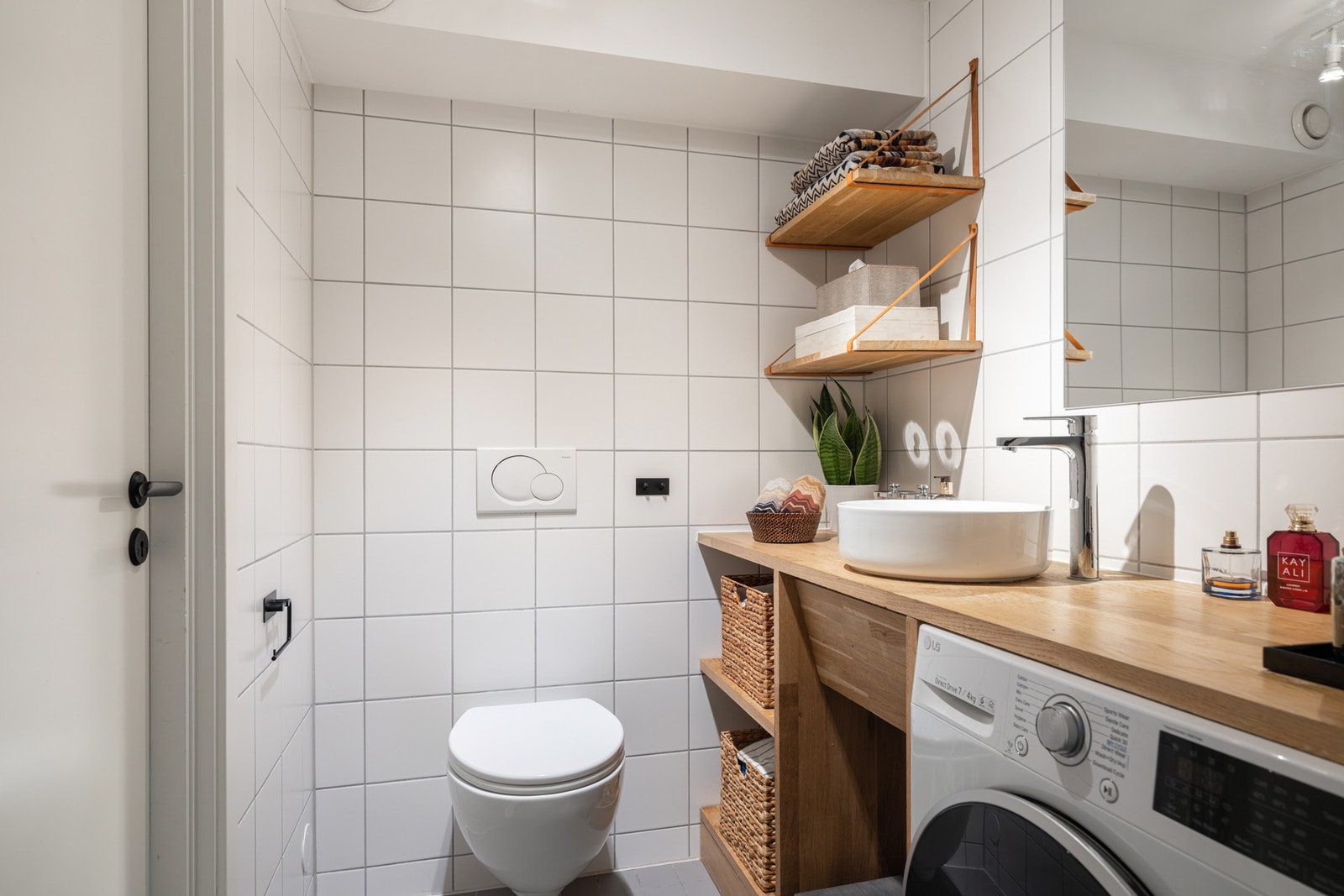 Et lyst toalettrom med opplegg for vaskemaskin og god lagringsplass. Galleribilde