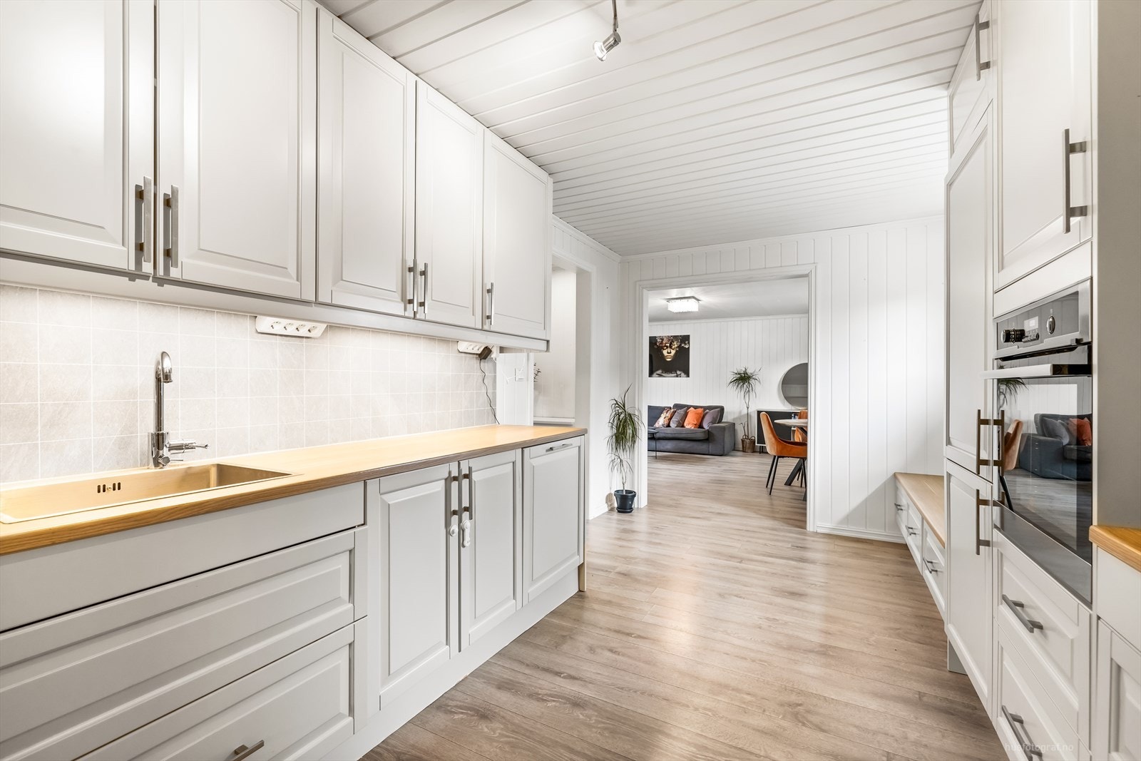 Moderne kjøkken med integrerte hvitevarer og åpen løsning mot stue. Galleribilde