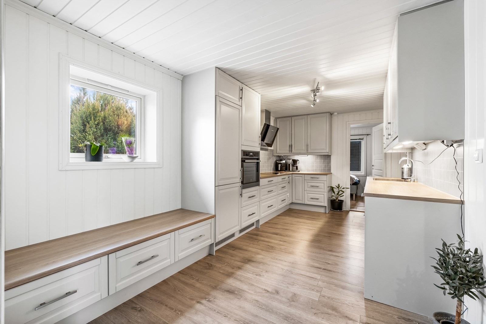 Lyst og moderne kjøkken med integrerte hvitevarer og rikelig benkeplass. Galleribilde