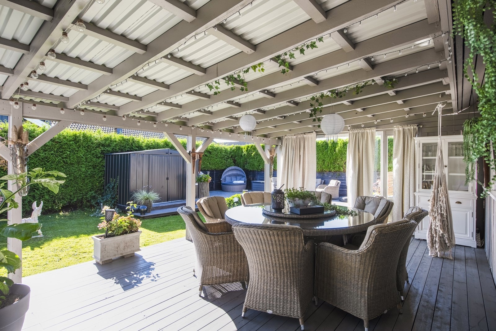 Terrasse i treverk med takoverbygg ca 29 m2 utenfor stuen og med utgang til hagen. Galleribilde