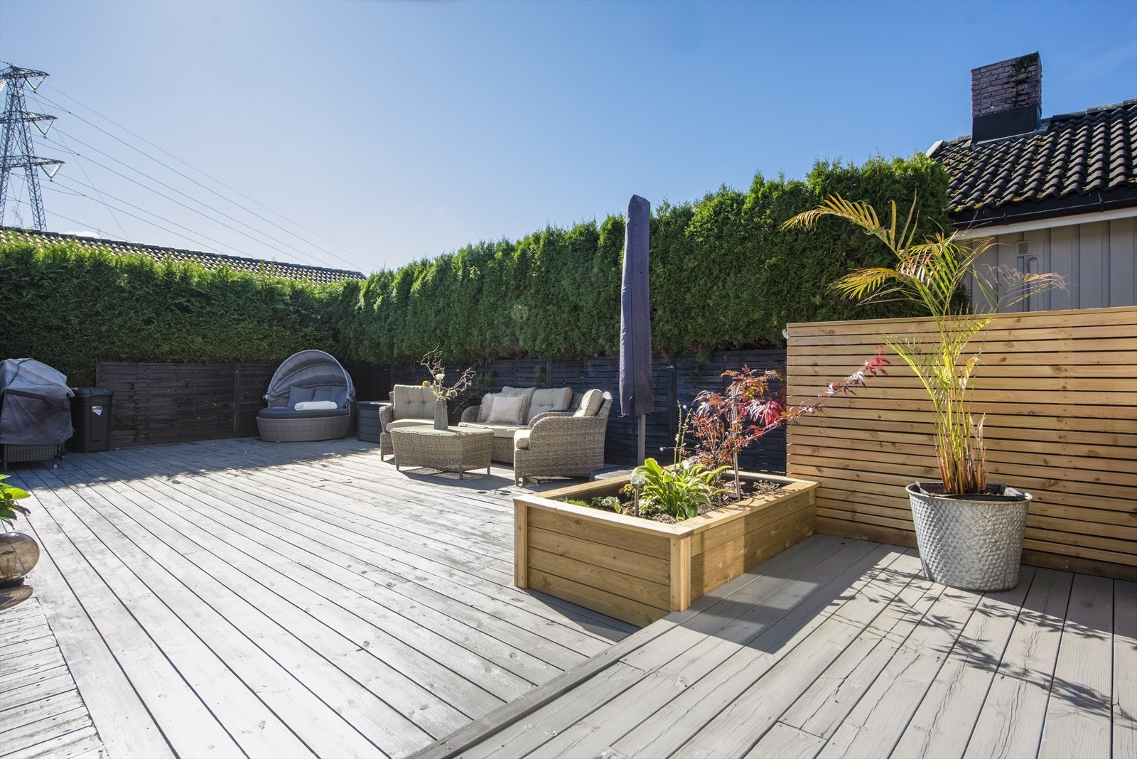 Nyere terrasse i treverk ca 64 m2 med blomsterkasser og levegger. Galleribilde