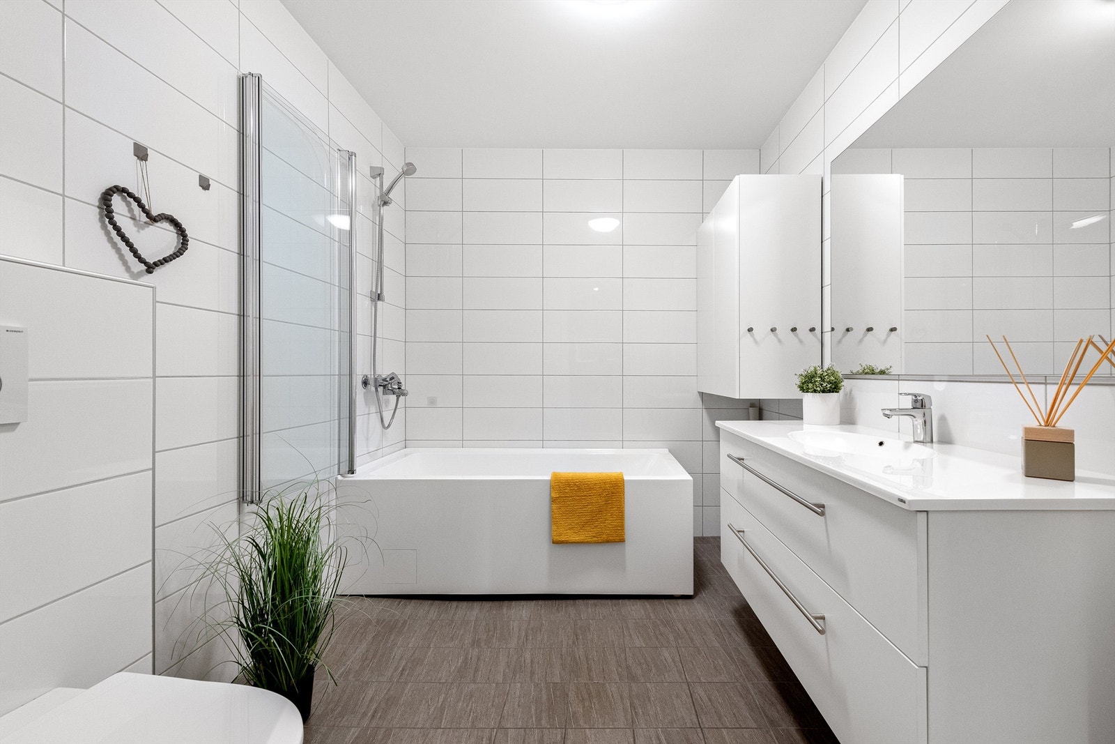 Romslig bad i 1. etasje med servantinnredning, speil med lys, frittstående badekar m/dusjvegg og vegghengt toalett Galleribilde